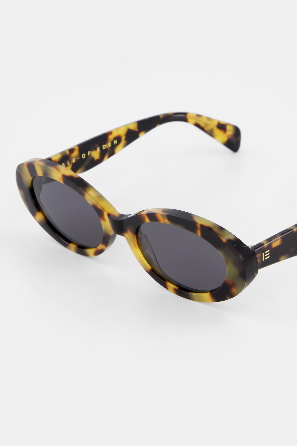 Close-up of Isle of Eden Frankie tortoise sunglasses showing curvy oval frame and brand lettering