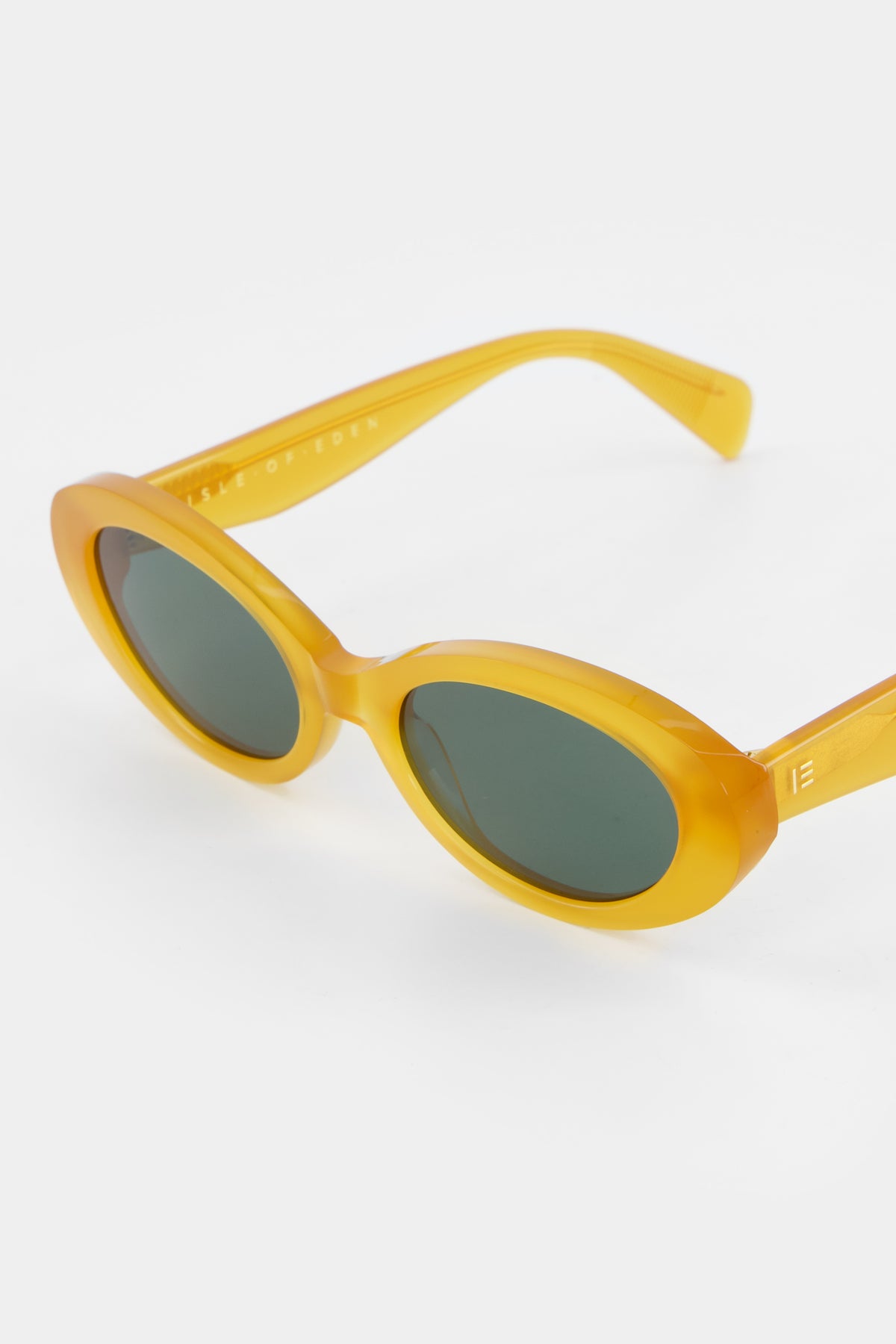 Close-up of Isle of Eden Frankie yellow sunglasses showing curvy oval frame and brand lettering