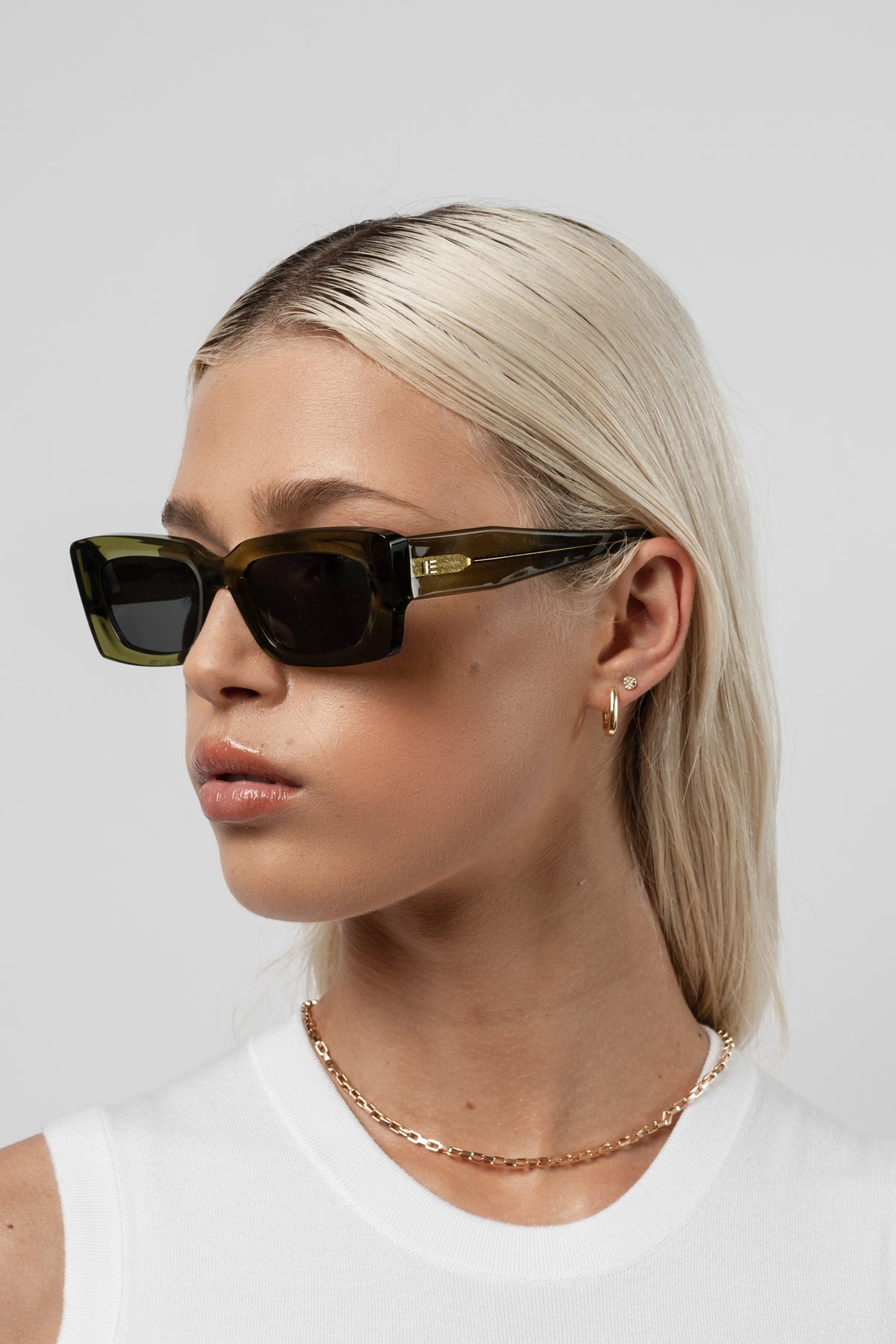 Female model wearing Isle of Eden Goldie green sunglasses, side profile portrait