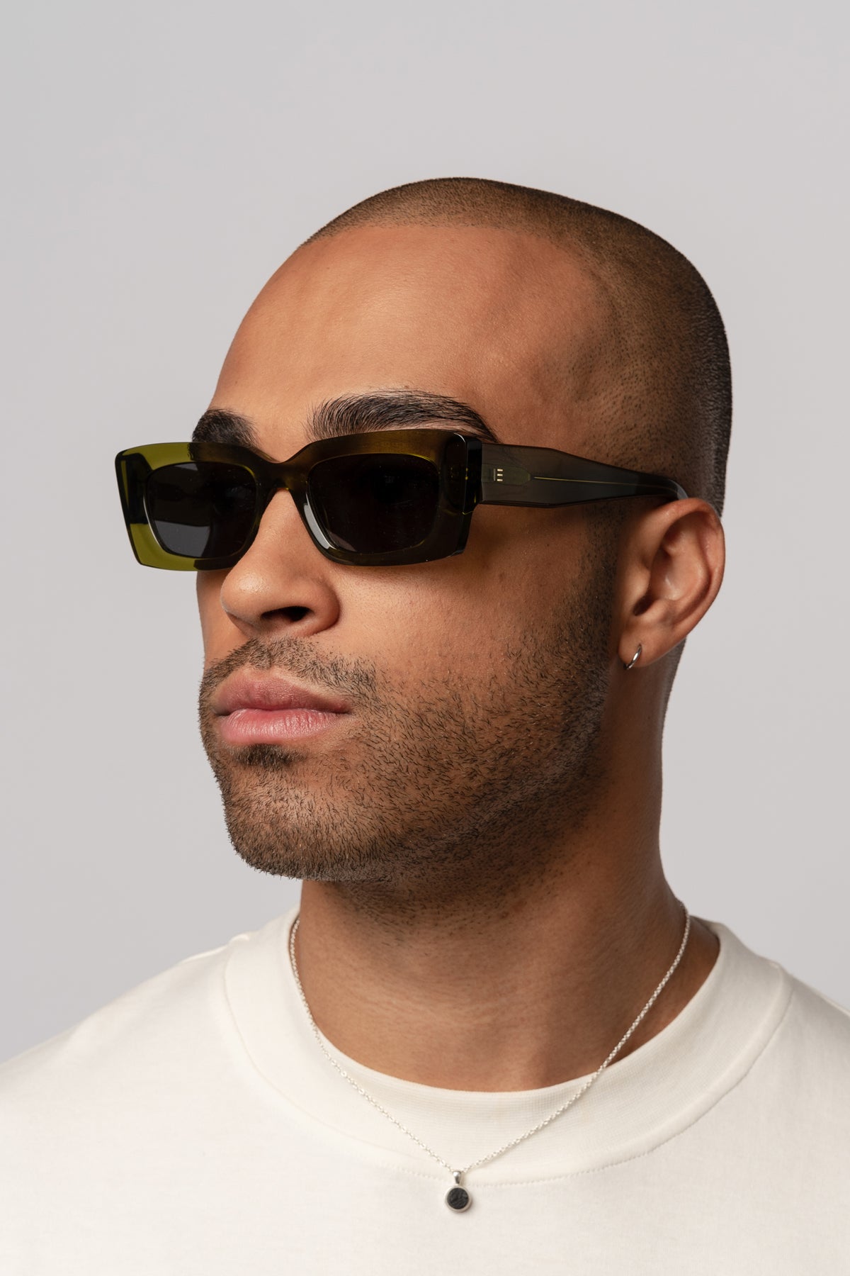 Male model wearing Isle of Eden Goldie green sunglasses, angled portrait