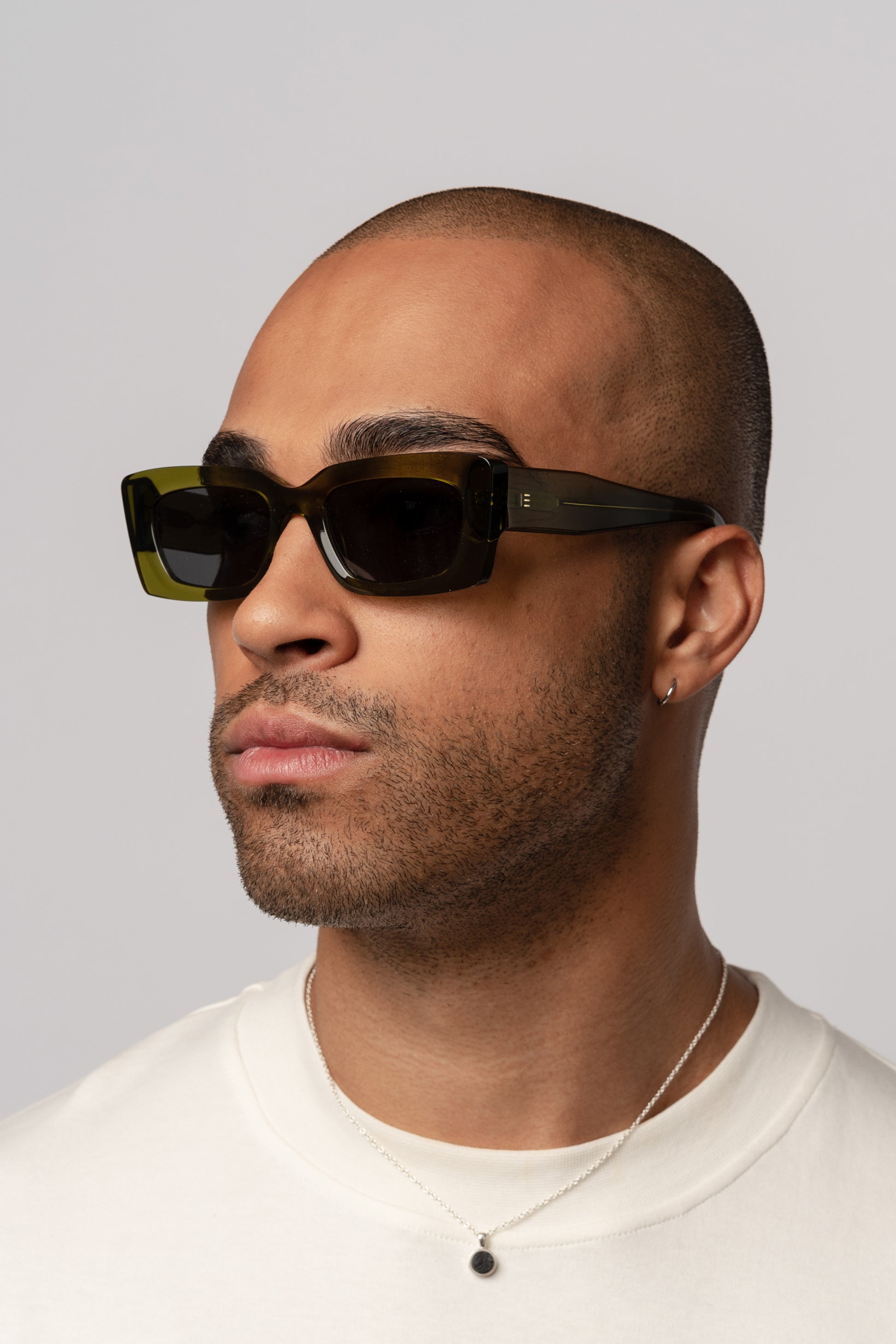 Male model wearing Isle of Eden Goldie green sunglasses, angled portrait