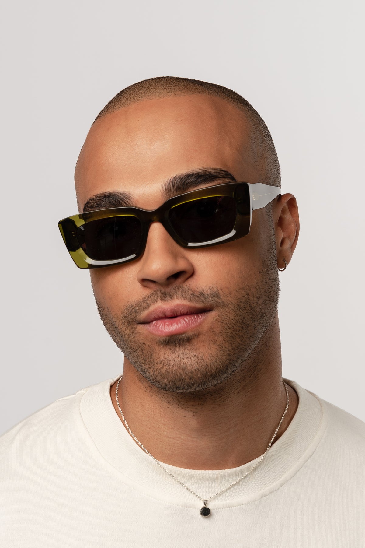 Male model wearing Isle of Eden Goldie green sunglasses, front-facing portrait looking directly at the camera