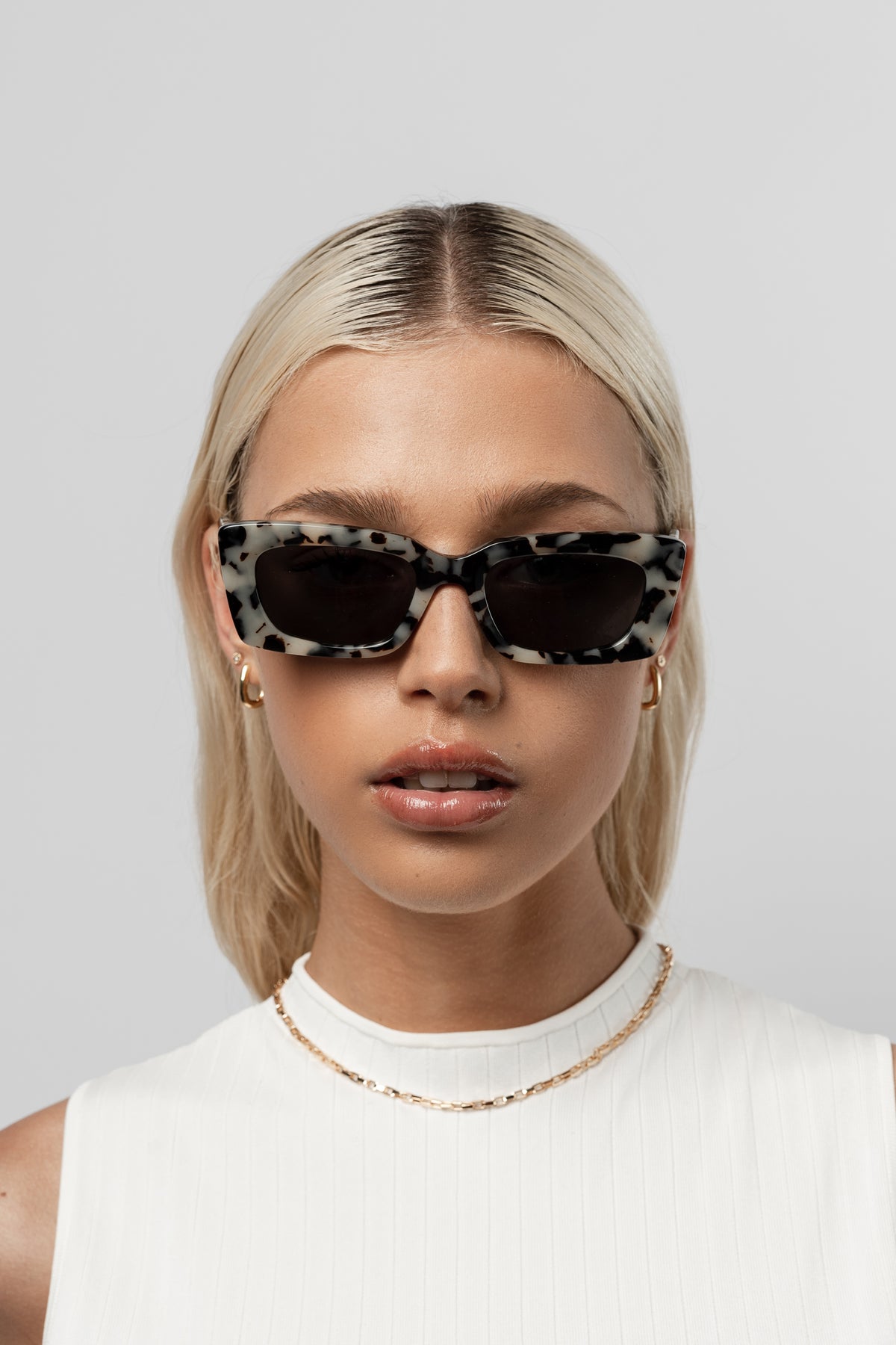 Female model wearing Isle of Eden Goldie white tortoise sunglasses, front-facing portrait
