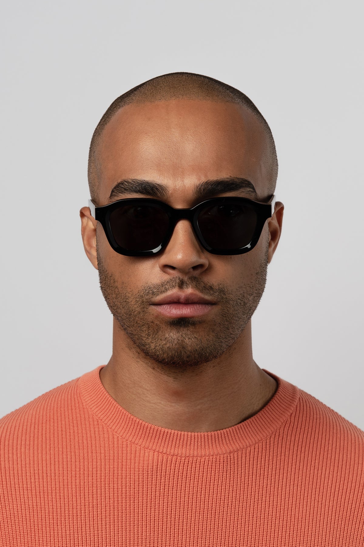 Male model wearing Isle of Eden Harley black sunglasses, front-facing portrait looking directly at the camera