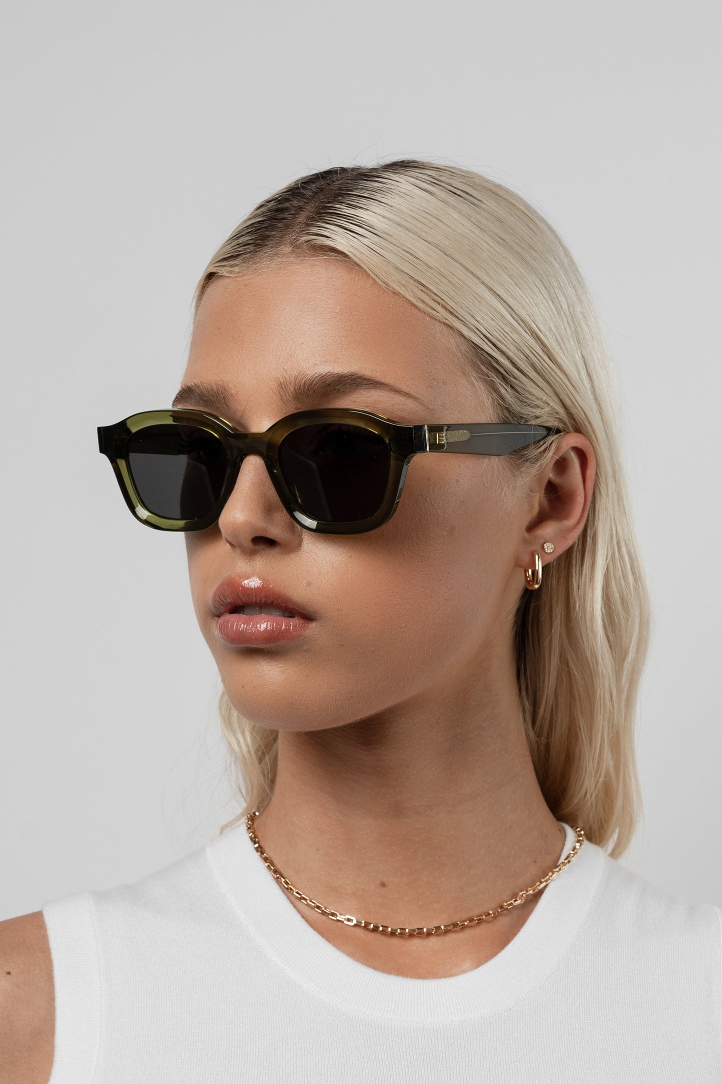 Female model wearing Isle of Eden Harley bottle green sunglasses, angled portrait