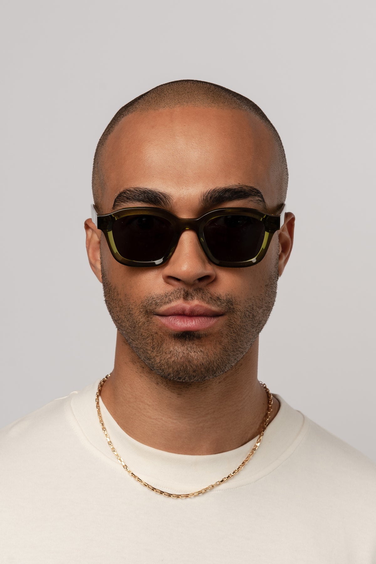 Male model wearing Isle of Eden Harley bottle green sunglasses, front-facing portrait looking directly at the camera