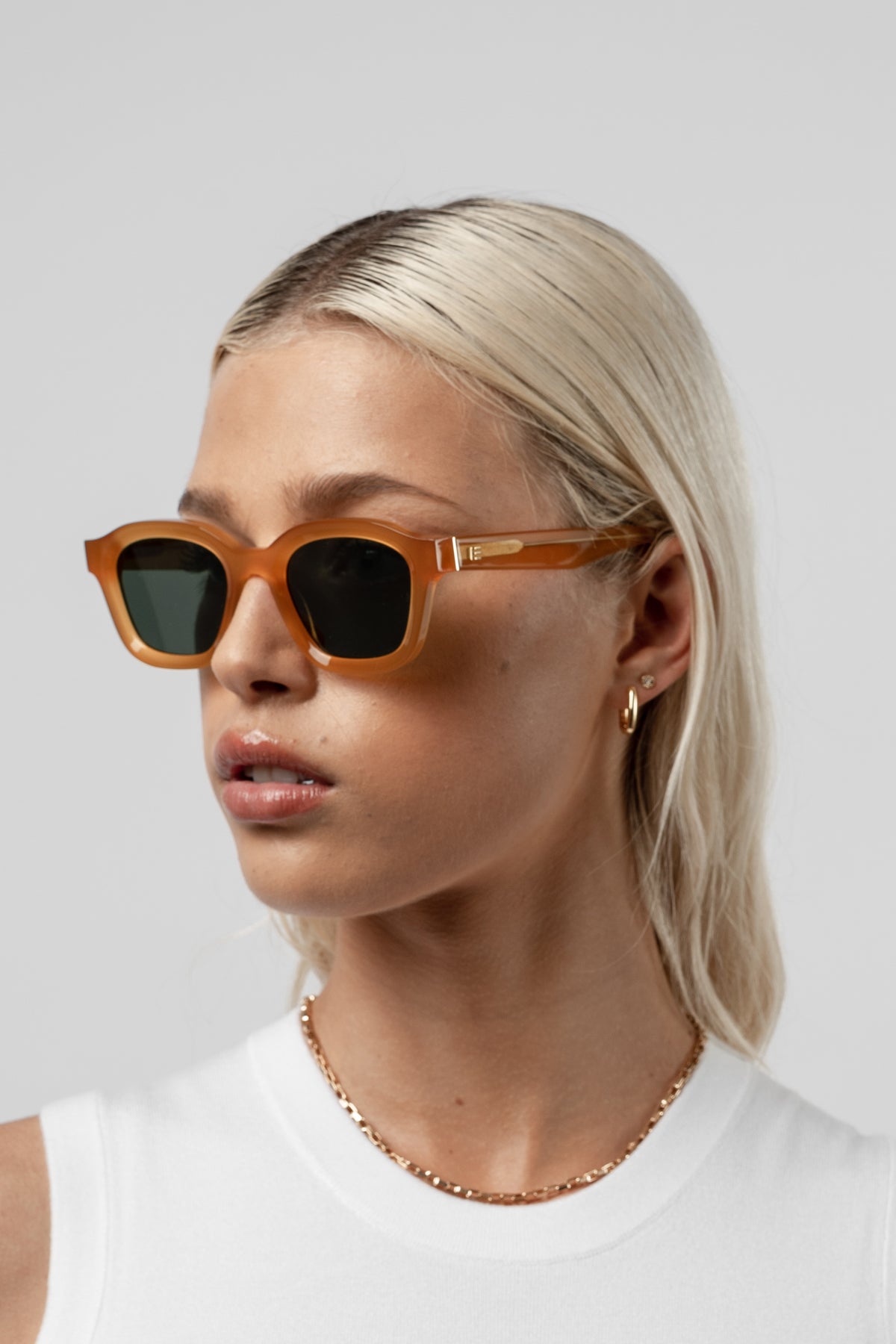 Female model wearing Isle of Eden Harley yellow sunglasses, angled portrait looking away