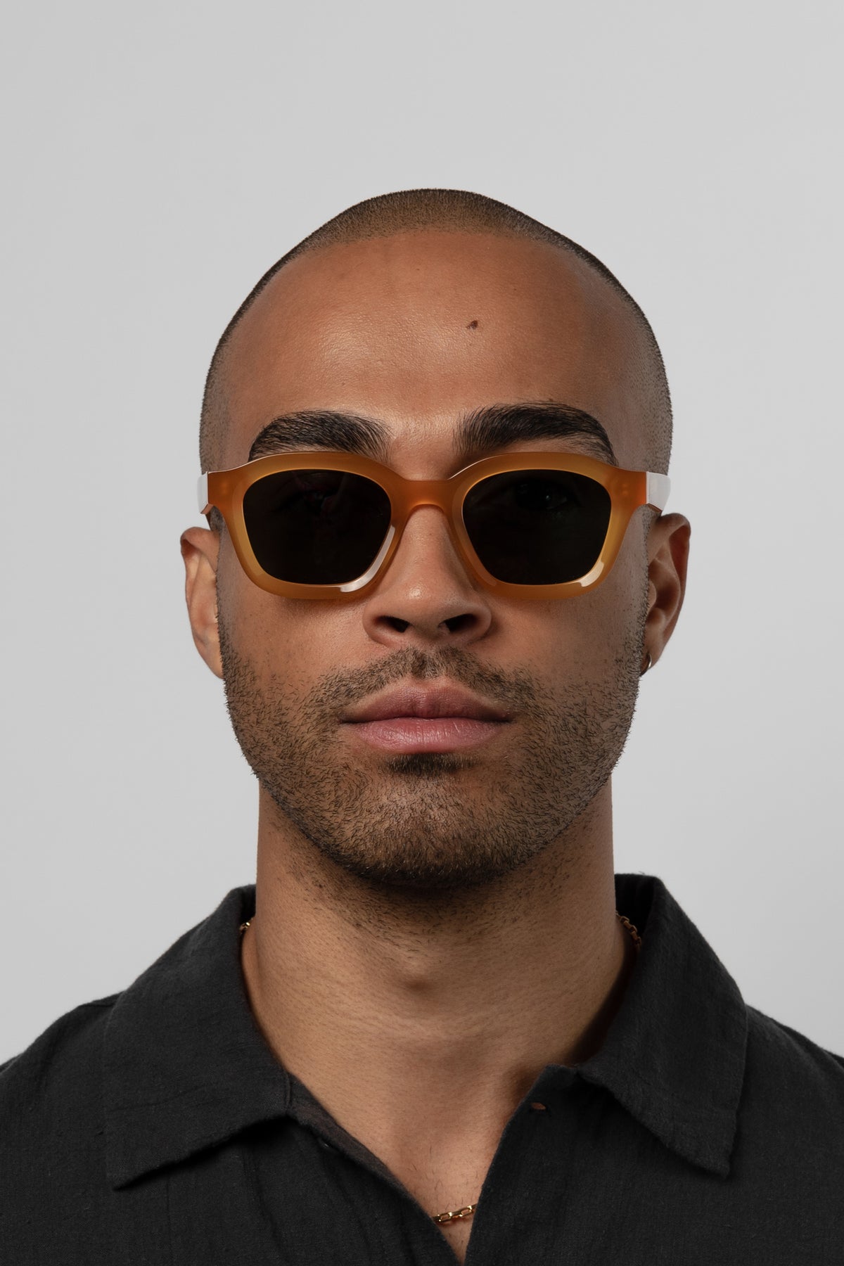 Male model wearing Isle of Eden Harley yellow sunglasses, front-facing portrait looking directly at the camera