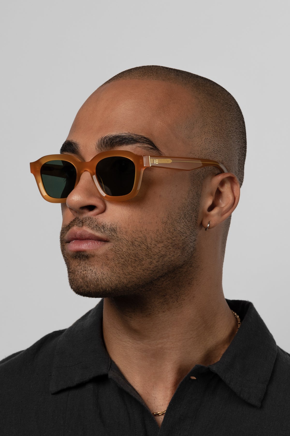 Male model wearing Isle of Eden Harley yellow sunglasses, angled portrait looking away