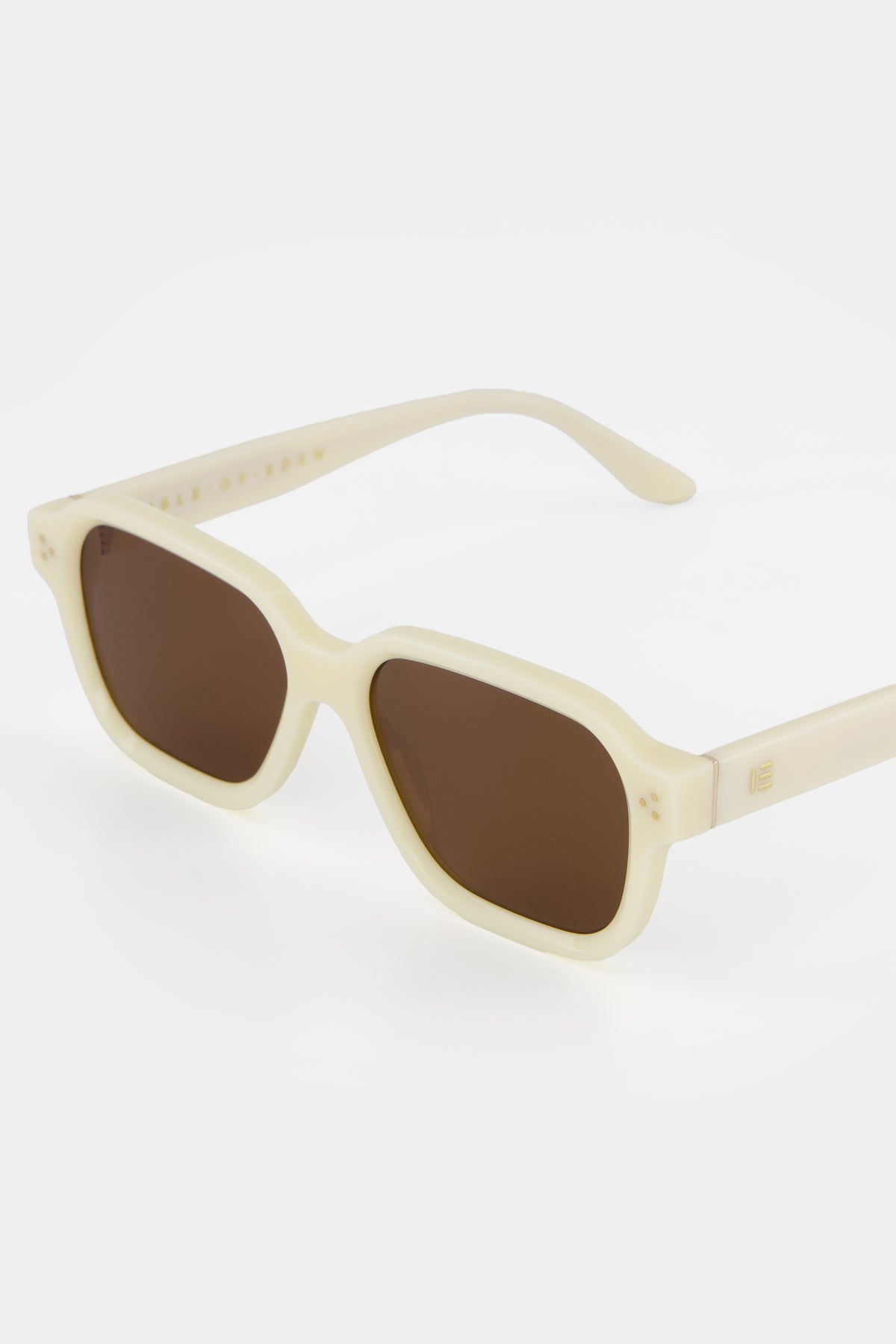 Close-up of Isle of Eden Jamie ivory sunglasses showing geometric frame and brand lettering