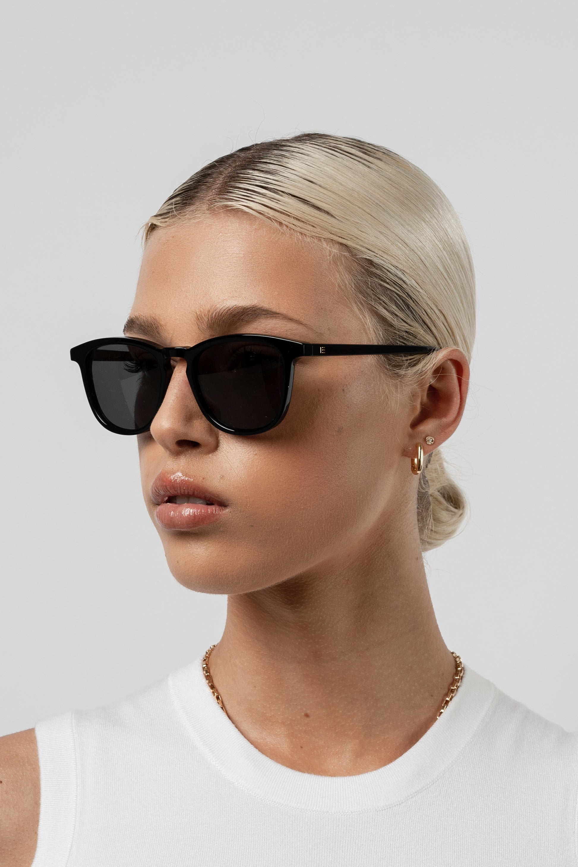 Woman wearing Isle of Eden Louis-Philippe black sunglasses, front-angled portrait against a white background