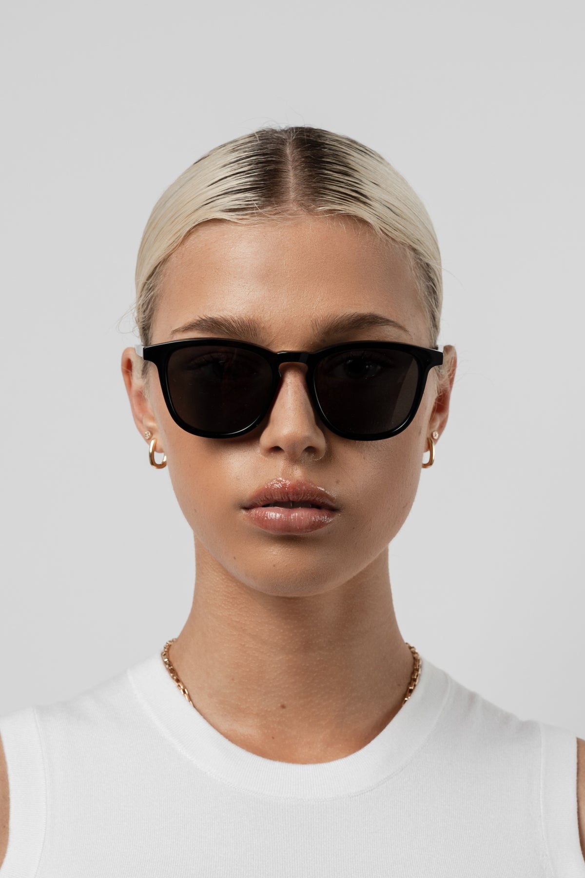Woman wearing Isle of Eden Louis-Philippe black sunglasses, front-facing portrait against a white background
