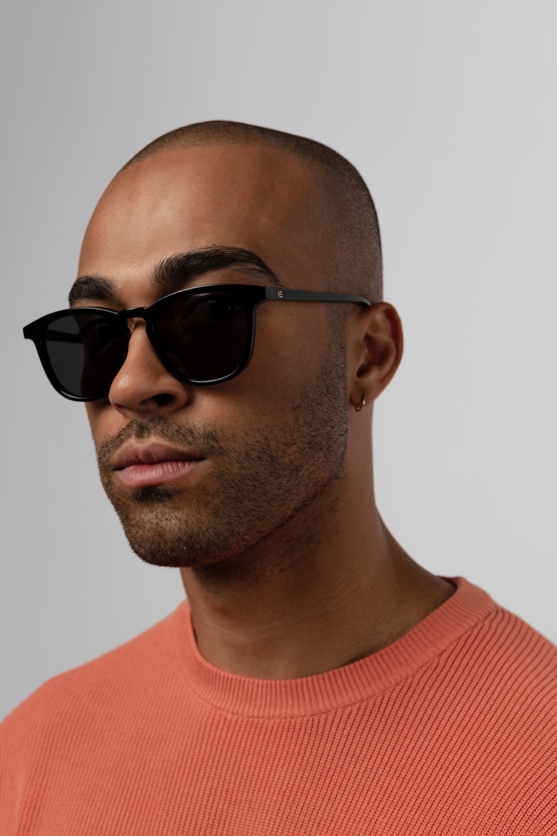 Man wearing Isle of Eden Louis-Philippe black sunglasses, angled side profile against a grey background