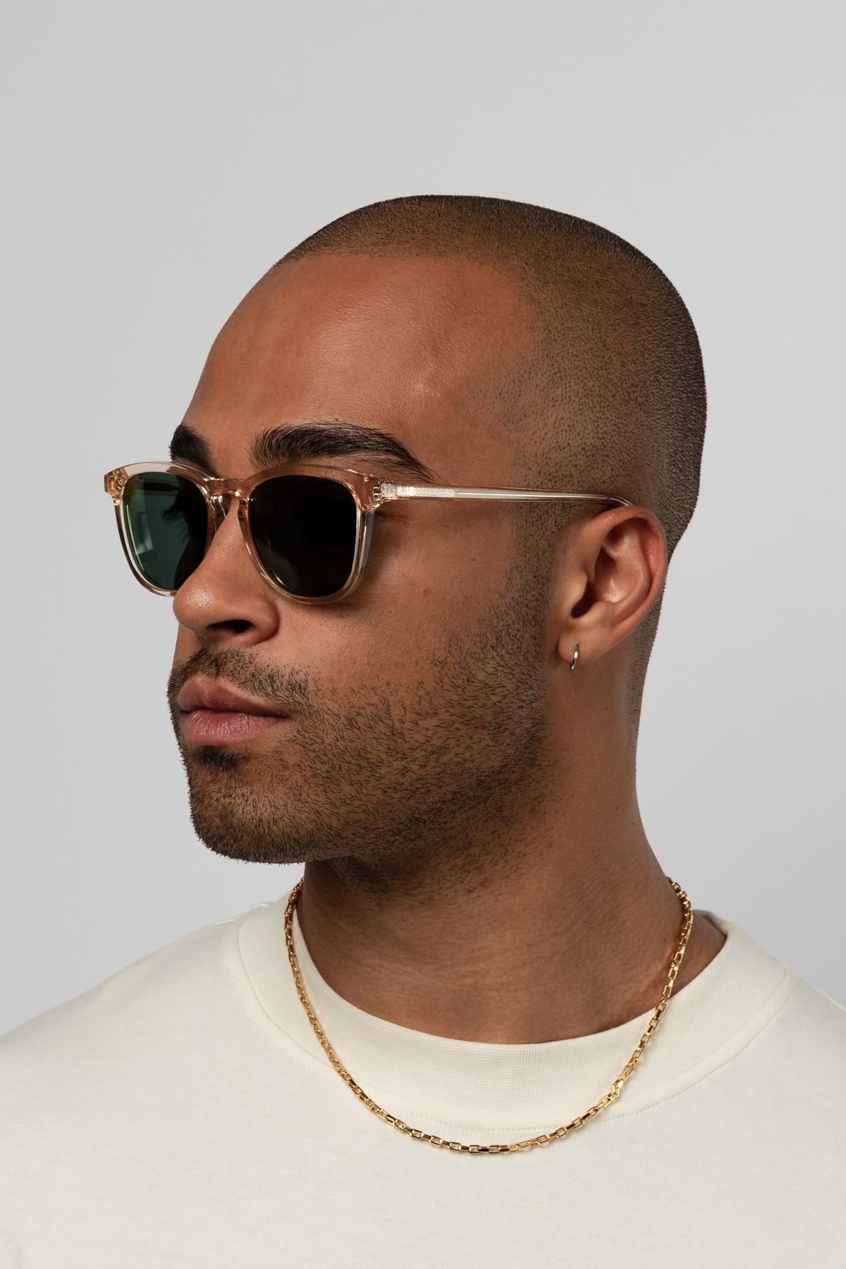 Man wearing Isle of Eden Louis-Philippe champagne sunglasses, angled portrait against a light background