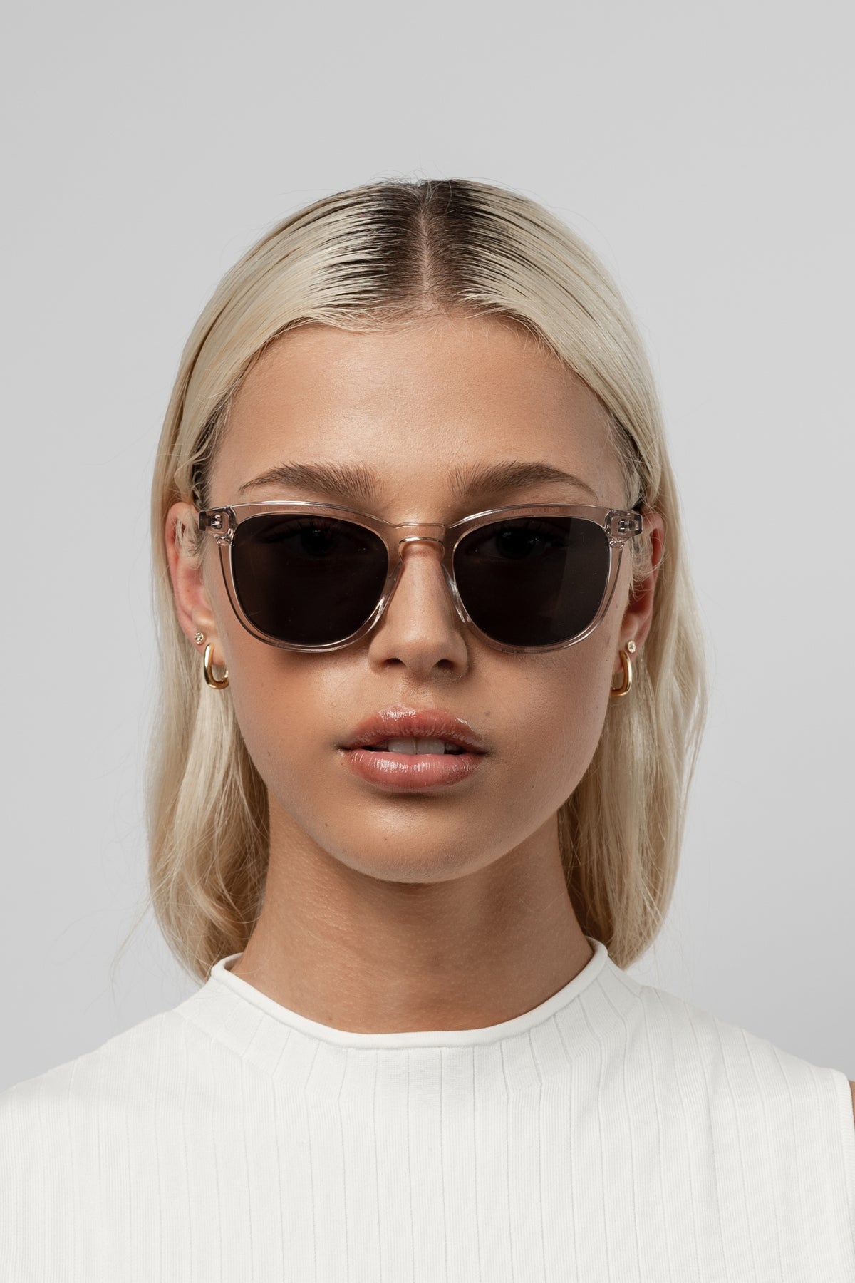 Woman wearing Isle of Eden Louis-Philippe sand sunglasses, front-facing portrait against a white background
