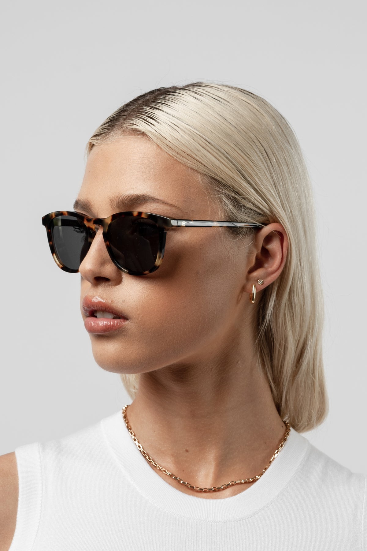 Woman wearing Isle of Eden Louis-Philippe tortoiseshell sunglasses, angled side profile against a light background