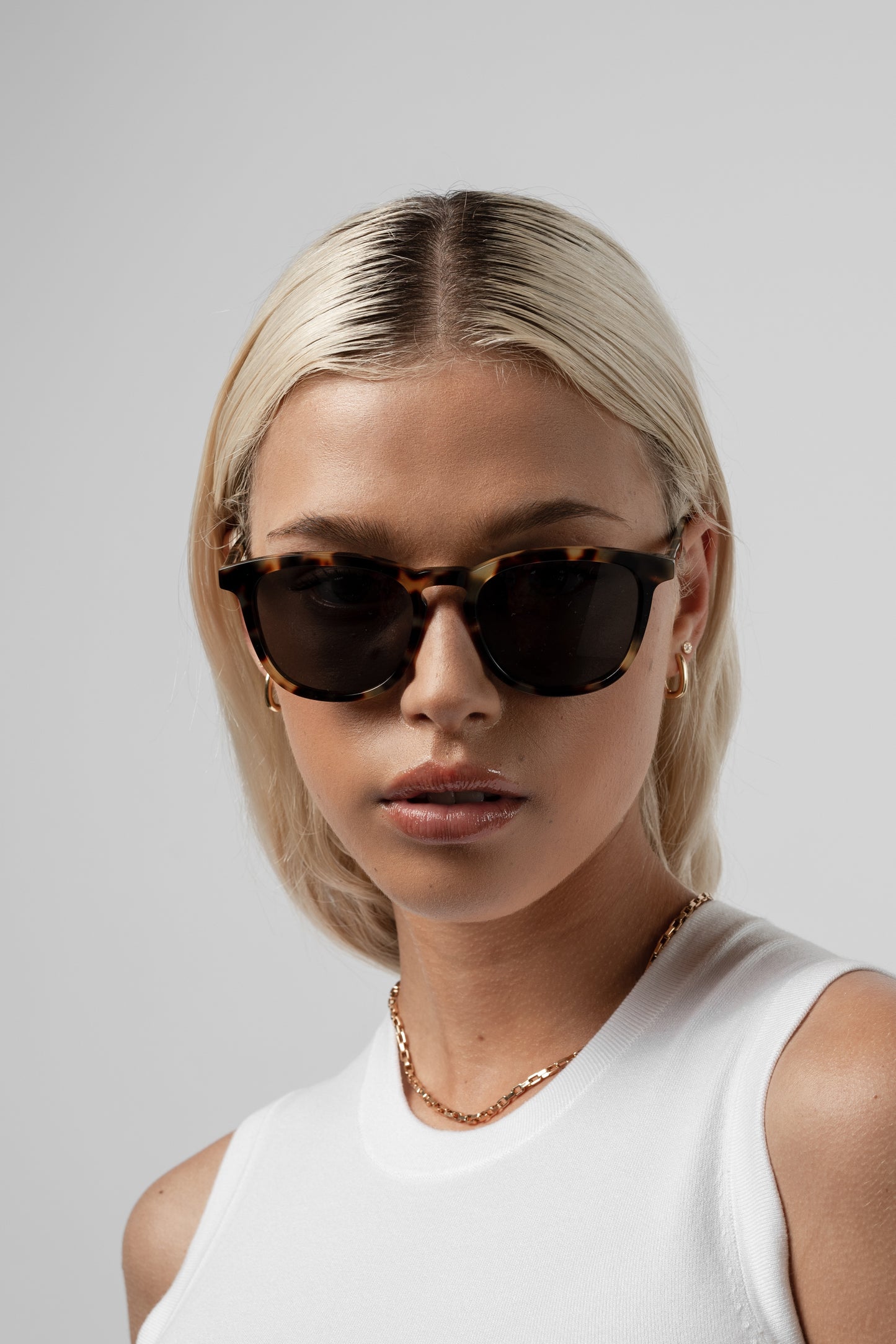 Woman wearing Isle of Eden Louis-Philippe tortoiseshell sunglasses, front-facing portrait against a light background