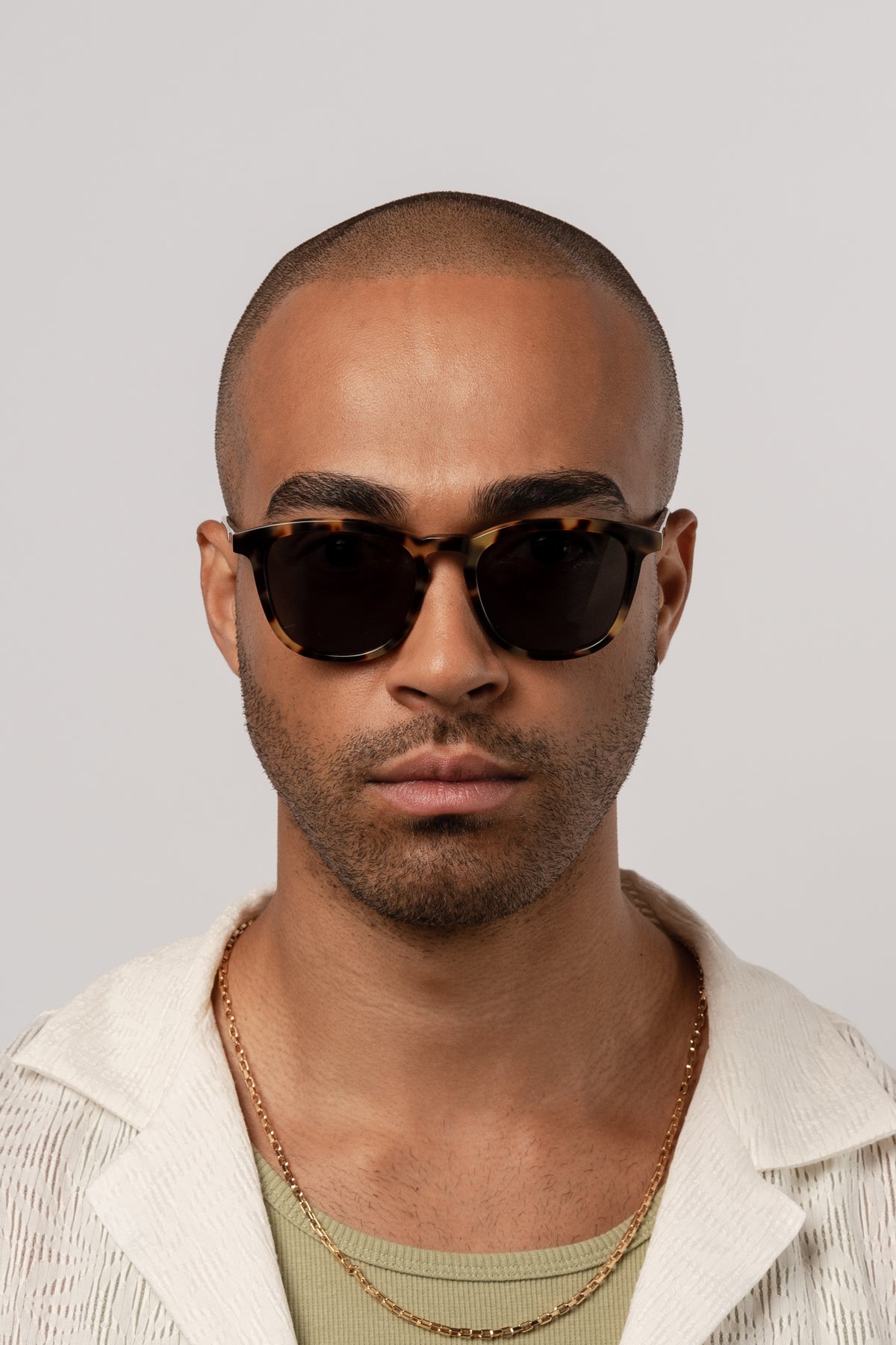 Man wearing Isle of Eden Louis-Philippe tortoiseshell sunglasses, front-facing portrait against a light background