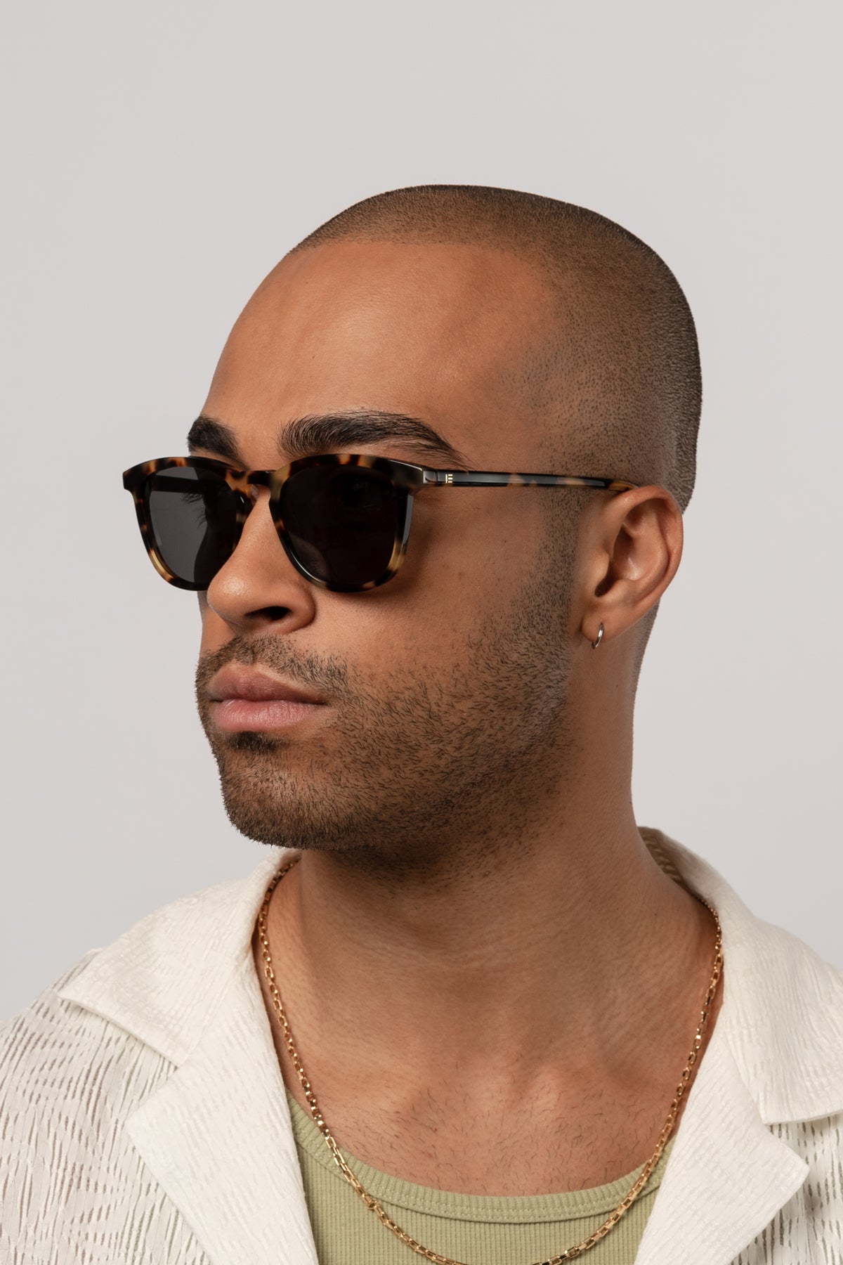 Man wearing Isle of Eden Louis-Philippe tortoiseshell sunglasses, angled portrait against a light background