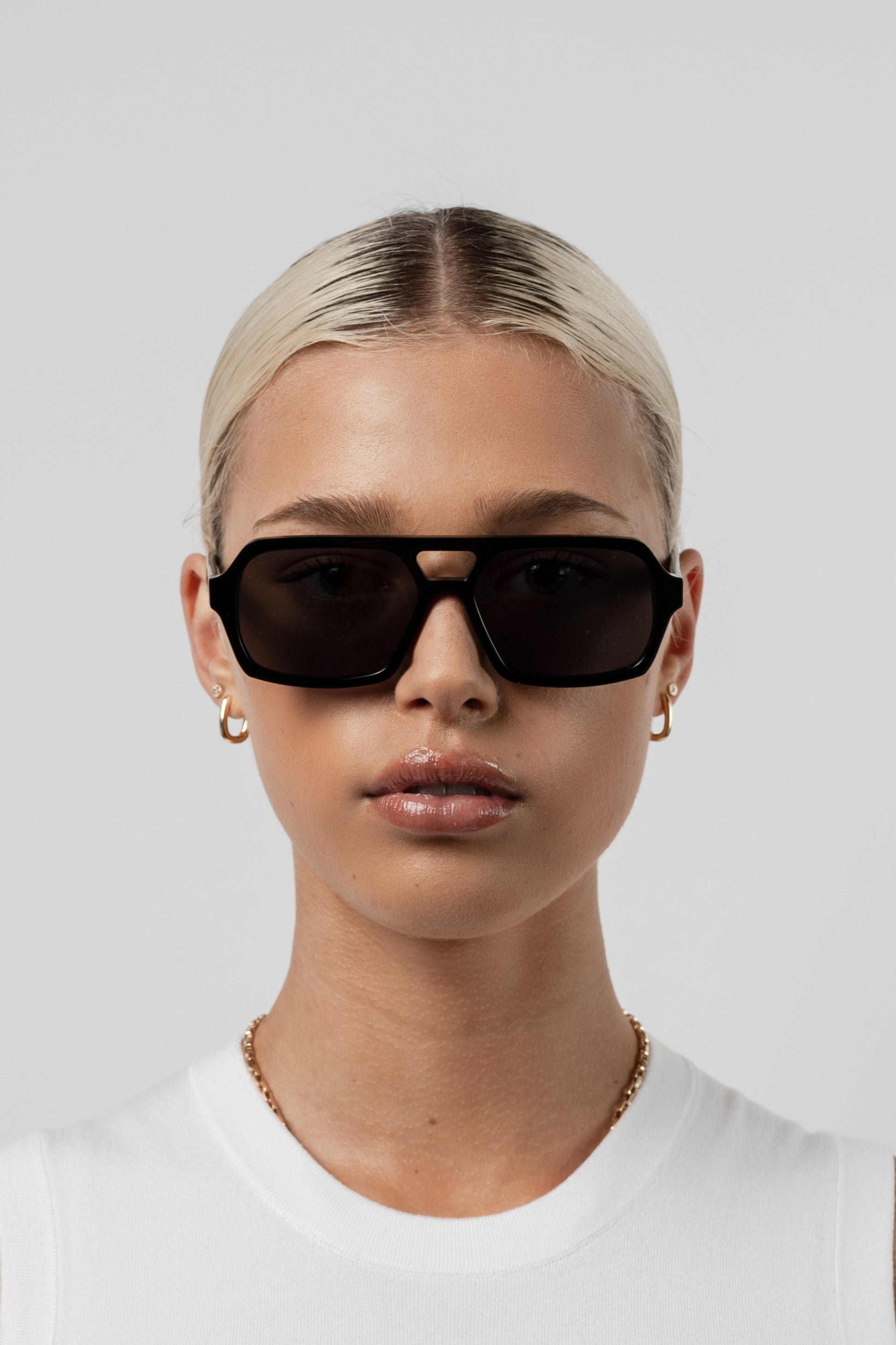 Female model wearing Isle of Eden Lola black sunglasses, front-facing portrait looking directly at the camera