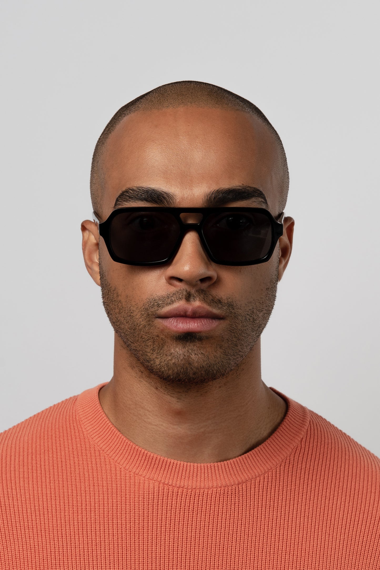 Male model wearing Isle of Eden Lola black sunglasses, front-facing portrait looking directly at the camera