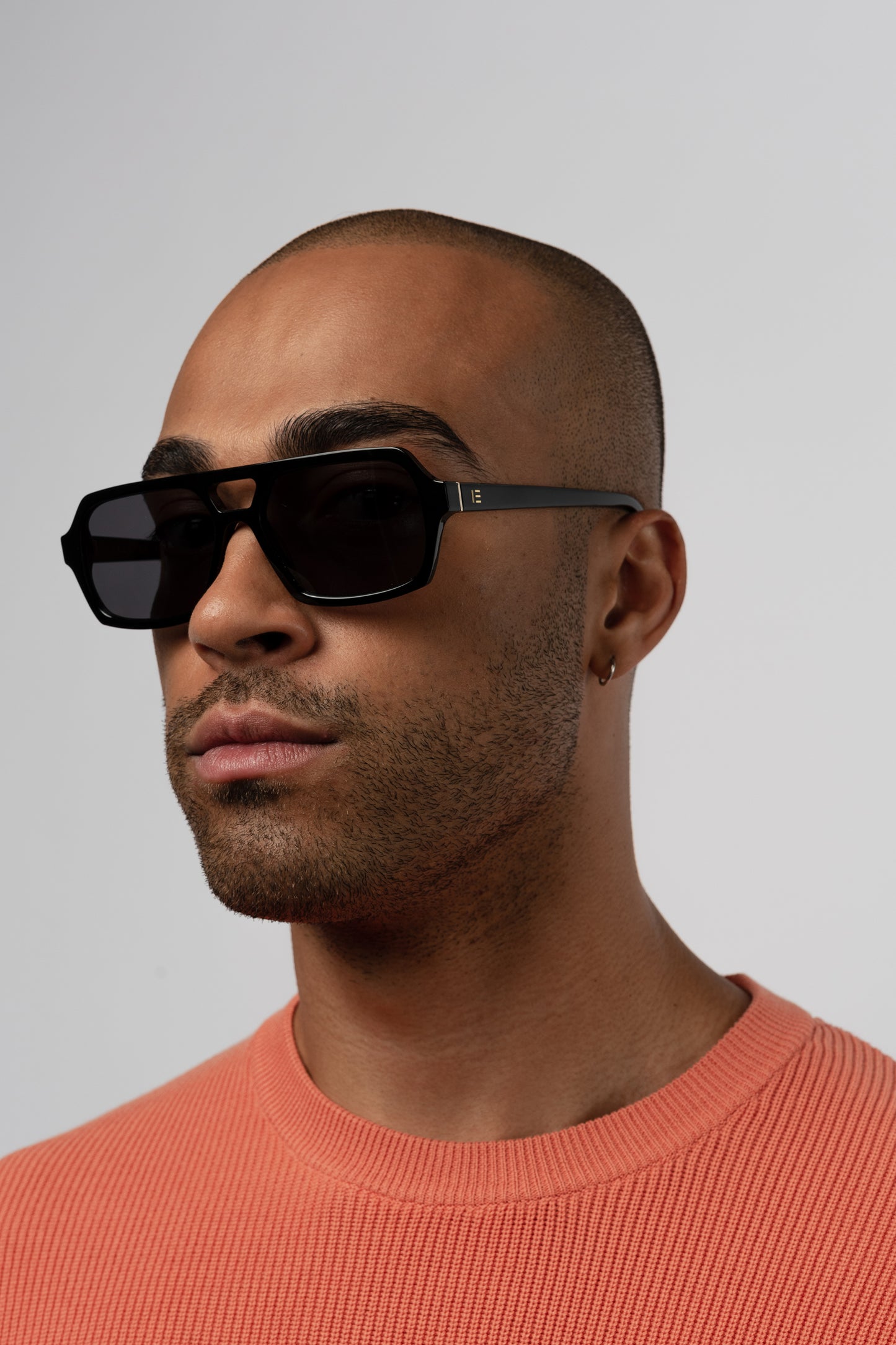 Male model wearing Isle of Eden Lola black sunglasses, angled portrait looking away