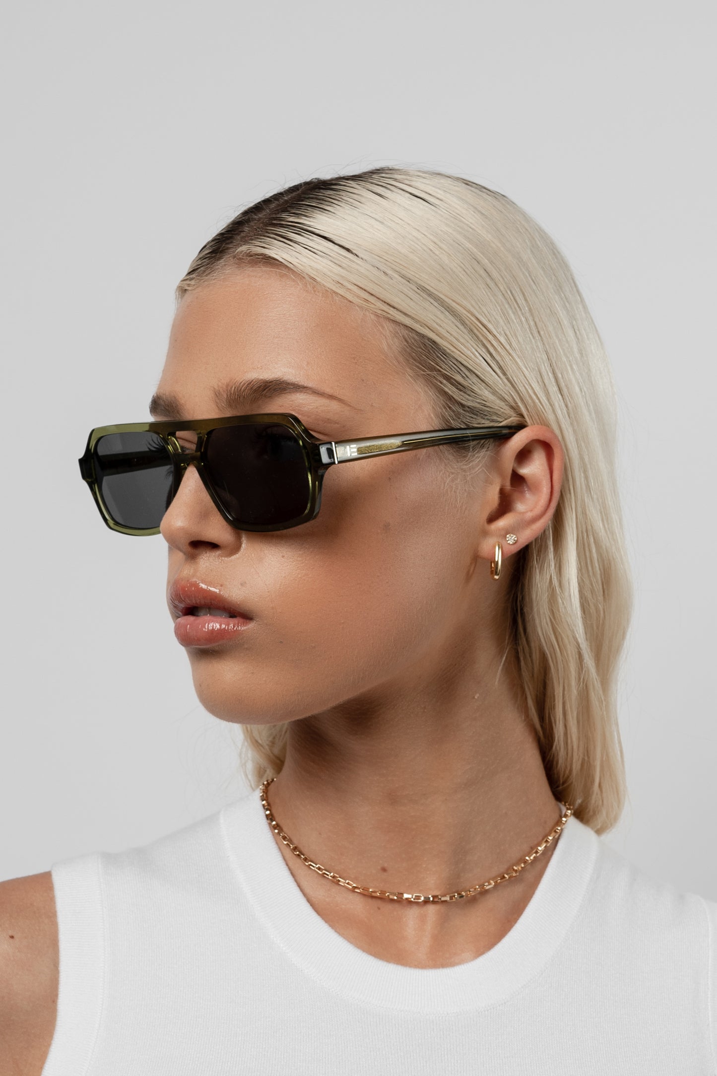 Female model wearing Isle of Eden Lola bottle green sunglasses, angled portrait looking away