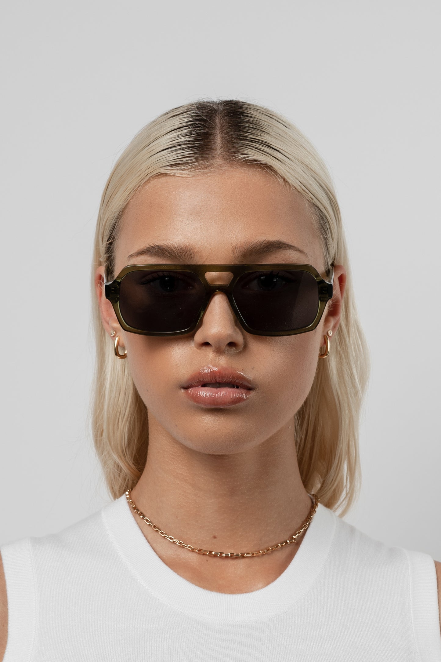 Female model wearing Isle of Eden Lola bottle green sunglasses, close front-facing portrait looking directly at the camera