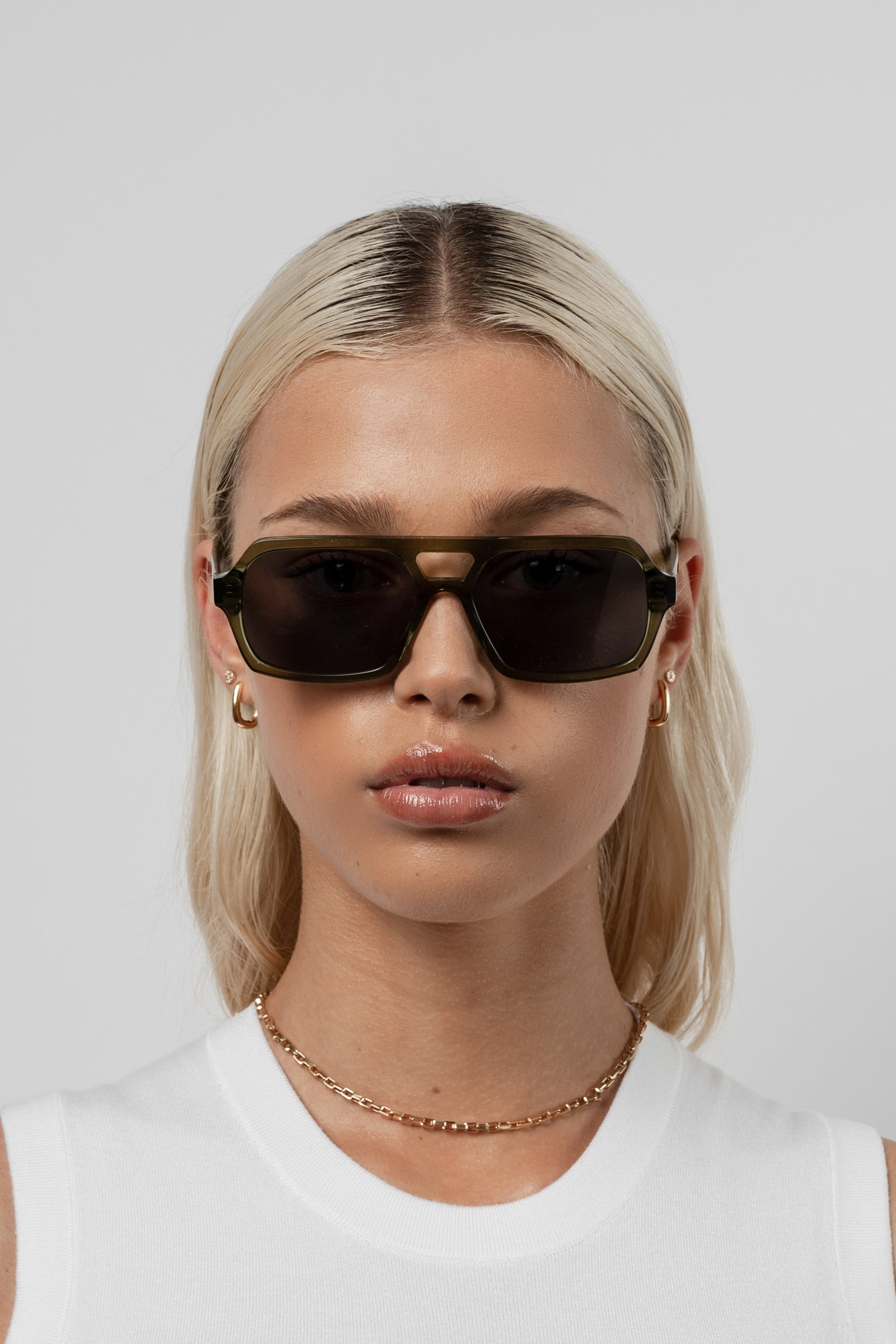 Female model wearing Isle of Eden Lola bottle green sunglasses, close front-facing portrait looking directly at the camera