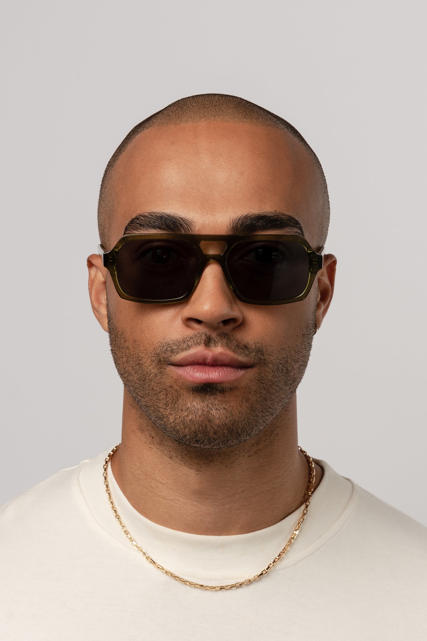 Male model wearing Isle of Eden Lola bottle green sunglasses, front-facing portrait looking directly at the camera