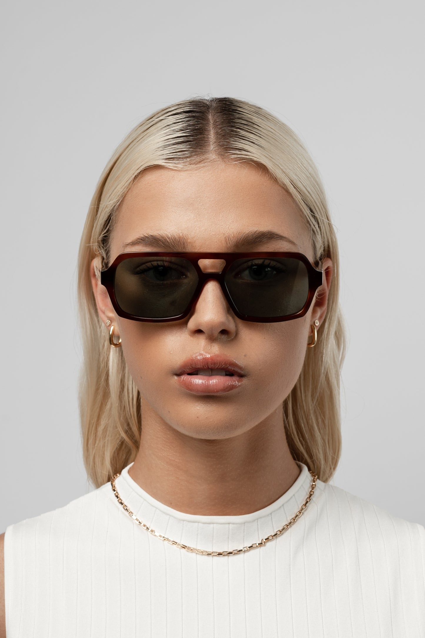 Female model wearing Isle of Eden Lola honey tortoise sunglasses, close front-facing portrait looking directly at the camera
