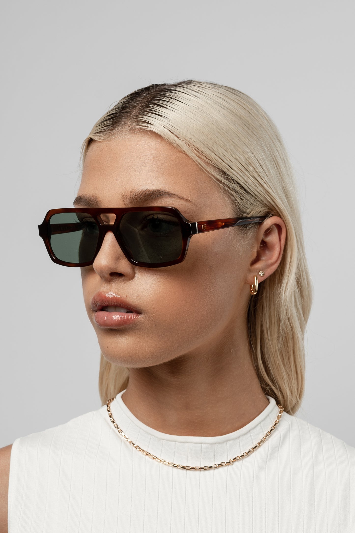 Female model wearing Isle of Eden Lola honey tortoise sunglasses, angled portrait