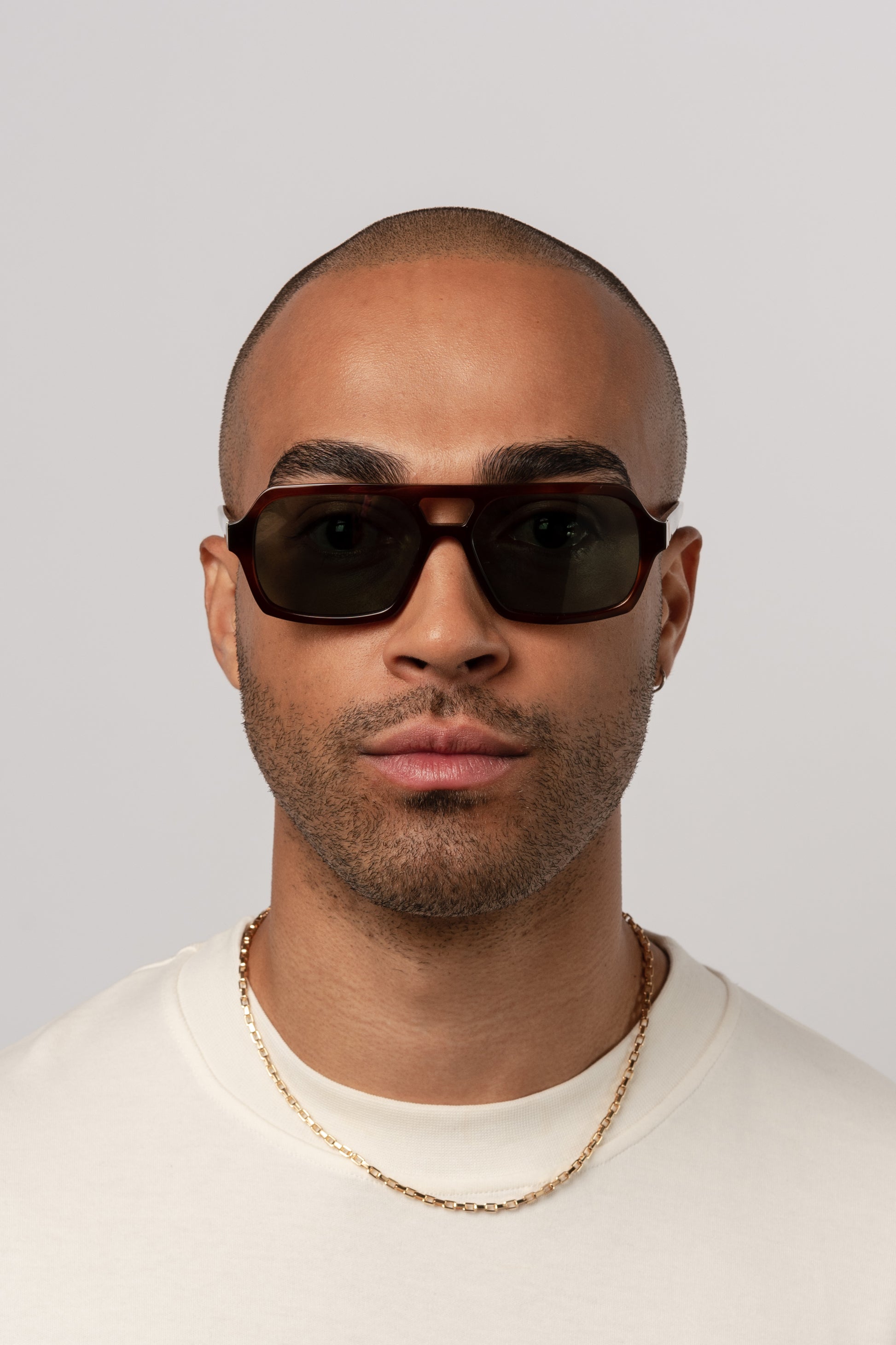 Male model wearing Isle of Eden Lola honey tortoise sunglasses, front-facing portrait looking directly at the camera