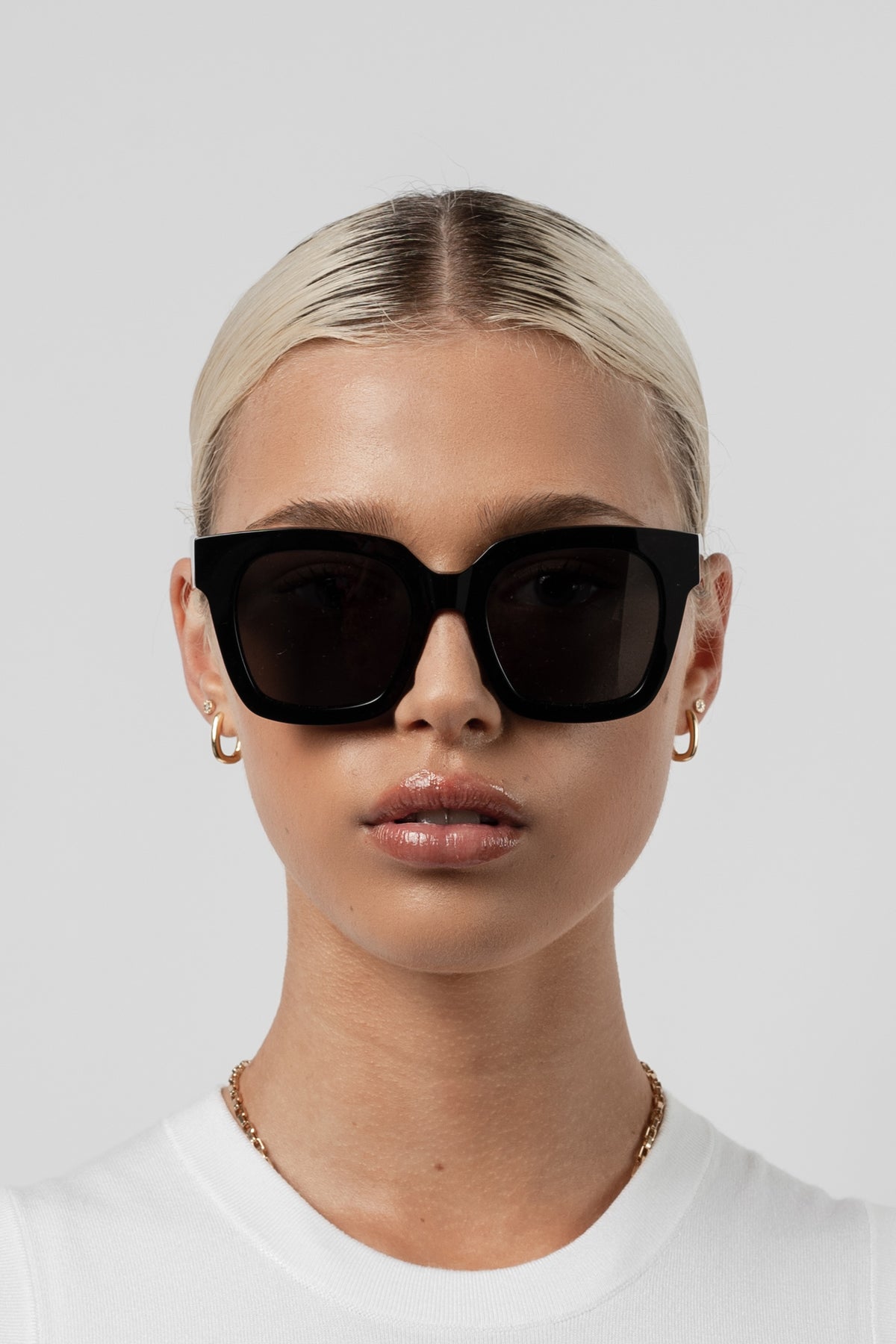 Female model wearing Isle of Eden Maleika black sunglasses, front-facing portrait looking directly at the camera