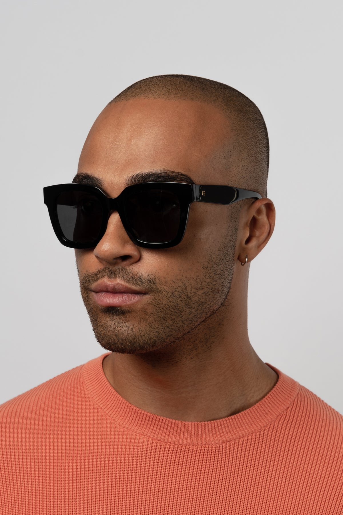 Male model wearing Isle of Eden Maleika black sunglasses, front-facing portrait looking directly at the camera