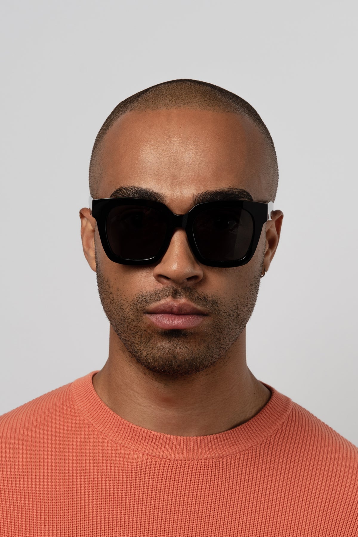 Male model wearing Isle of Eden Maleika black sunglasses, close front-facing portrait