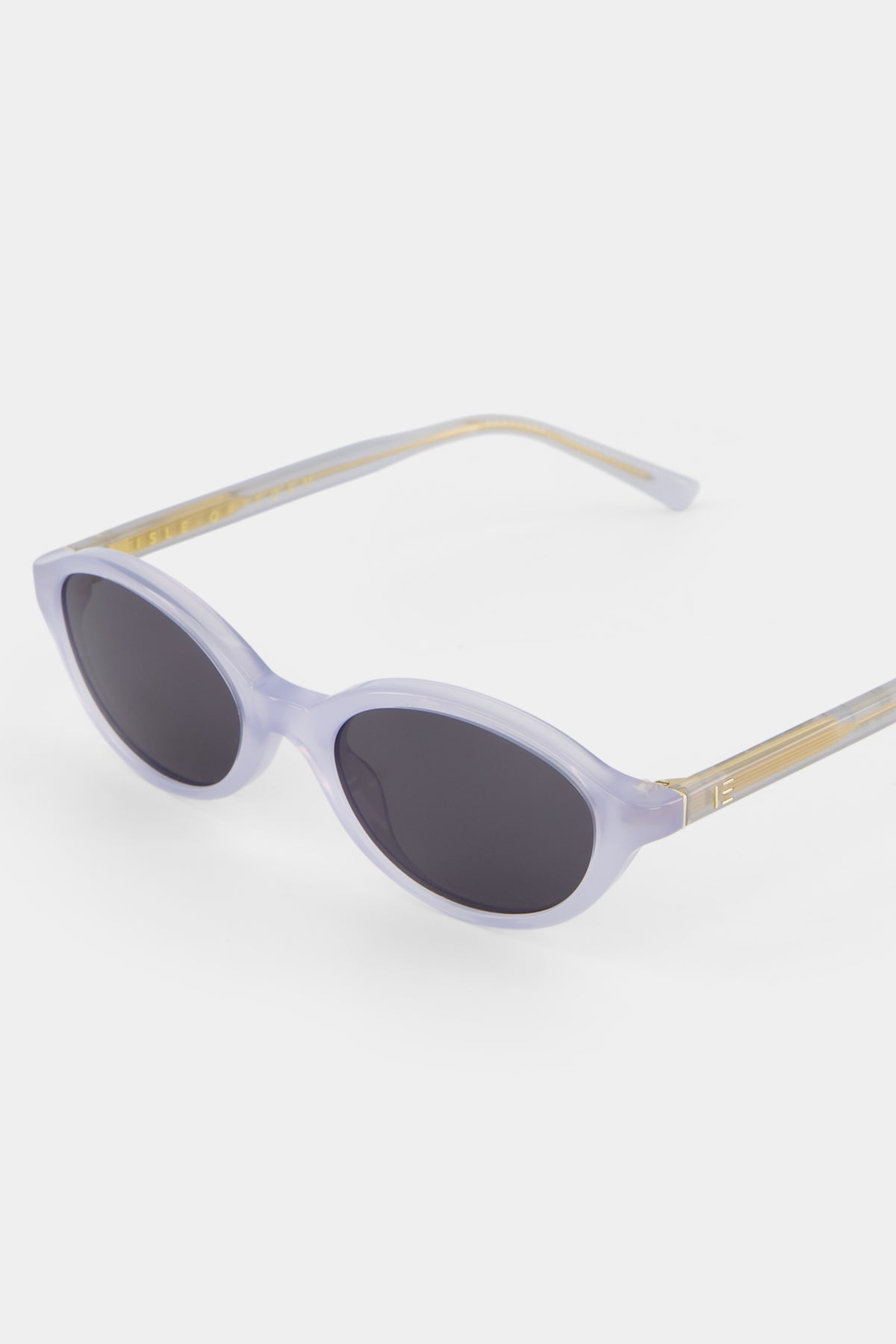 Close-up of Isle of Eden Mirabel baby blue sunglasses showing sleek oval frame and brand lettering