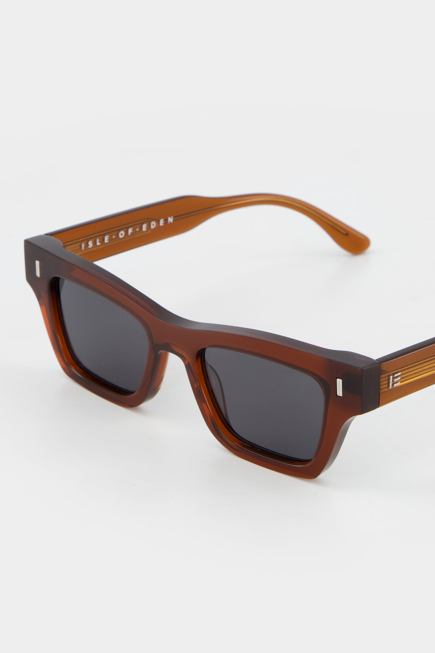Close-up of Isle of Eden Olli brown sunglasses showing low-profile art-deco frame and brand lettering