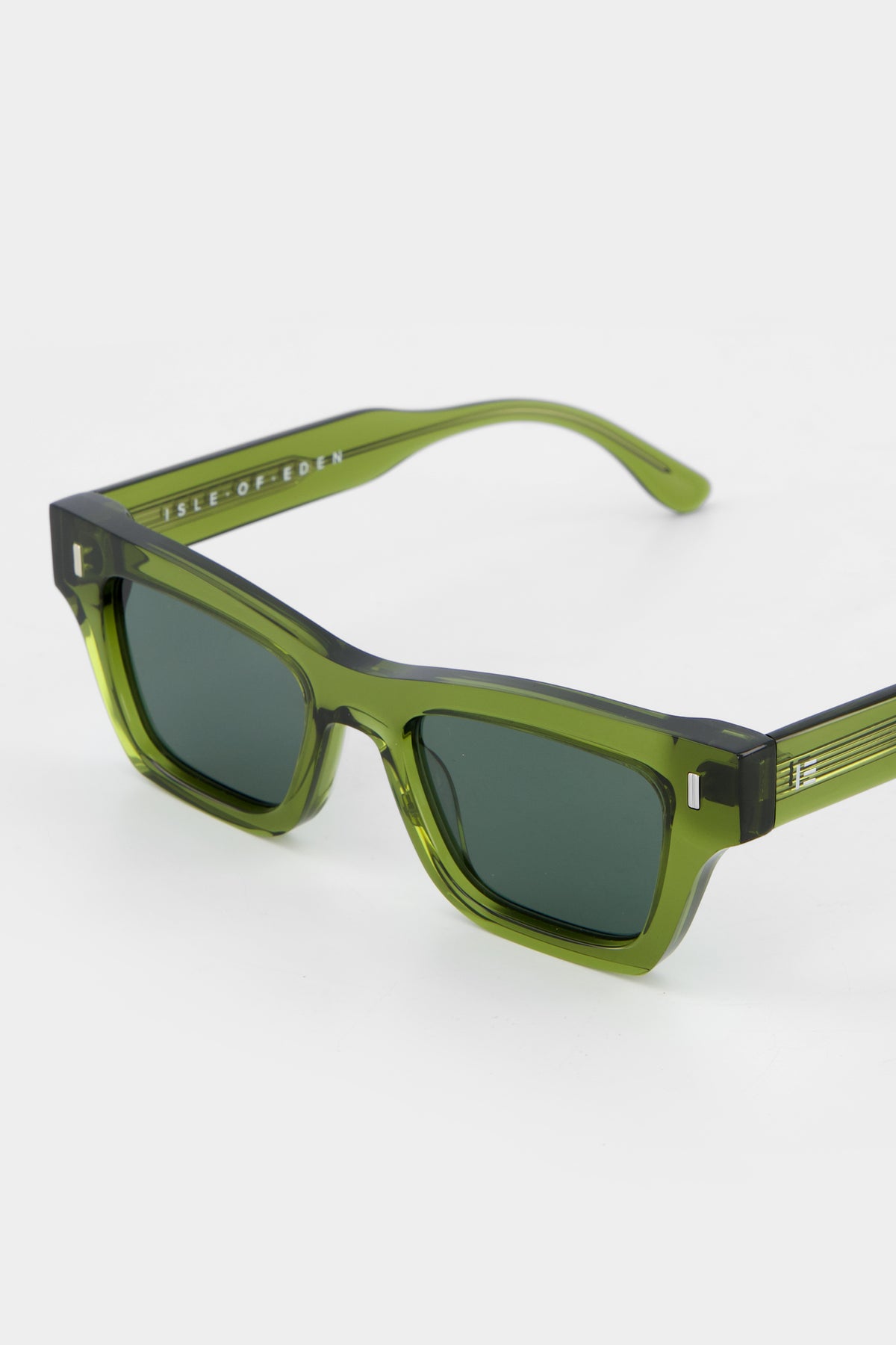 Close-up of Isle of Eden Olli bottle green sunglasses showing low-profile art-deco frame and brand lettering