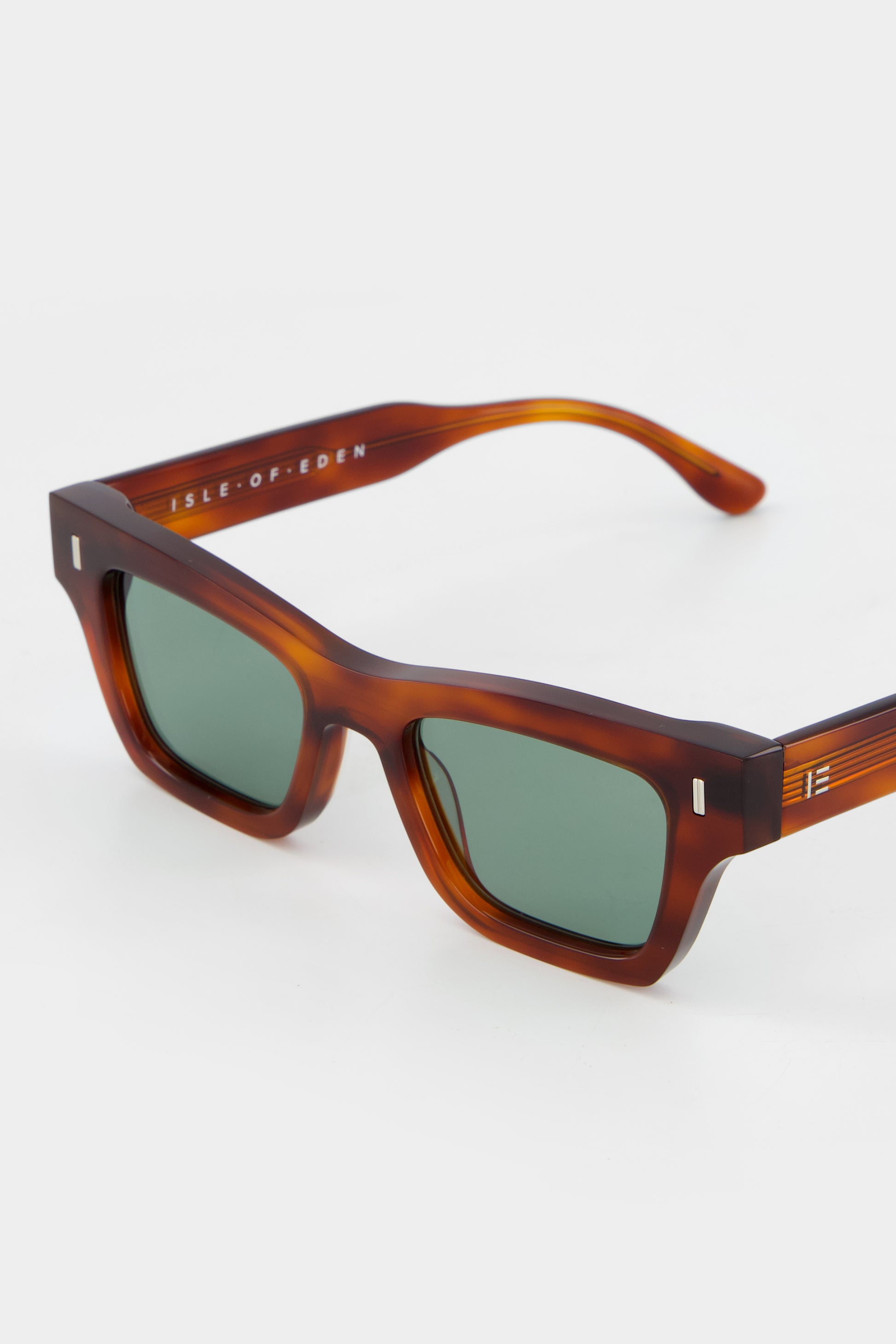 Close-up of Isle of Eden Olli honey tortoise sunglasses showing low-profile art-deco frame and brand lettering