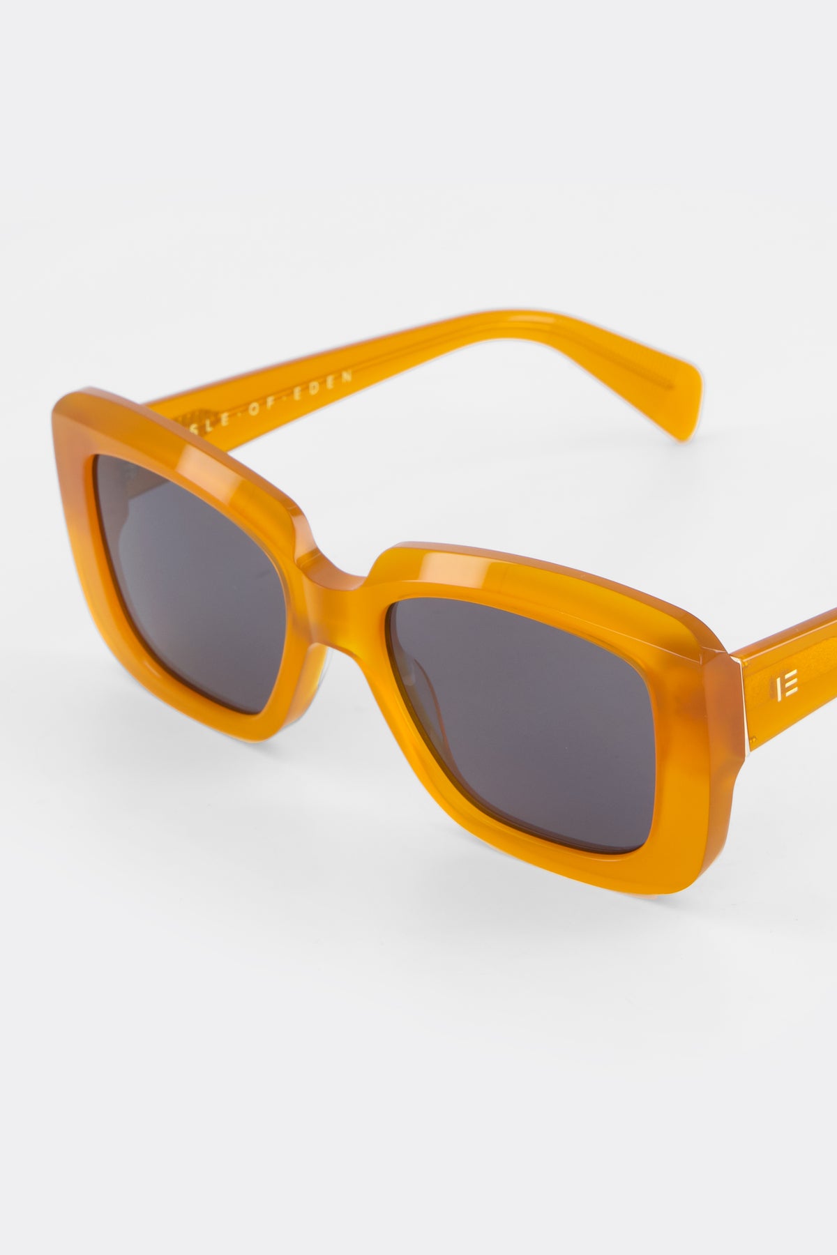 Close-up of Isle of Eden Pia peach sunglasses showing bold rectangular frame and brand lettering