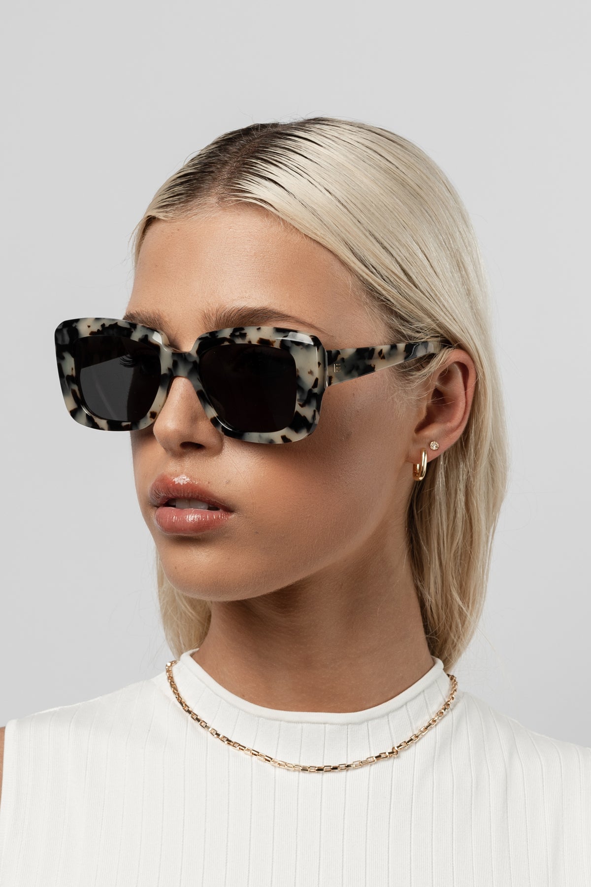 Female model wearing Isle of Eden Pia white tortoise sunglasses, angled portrait