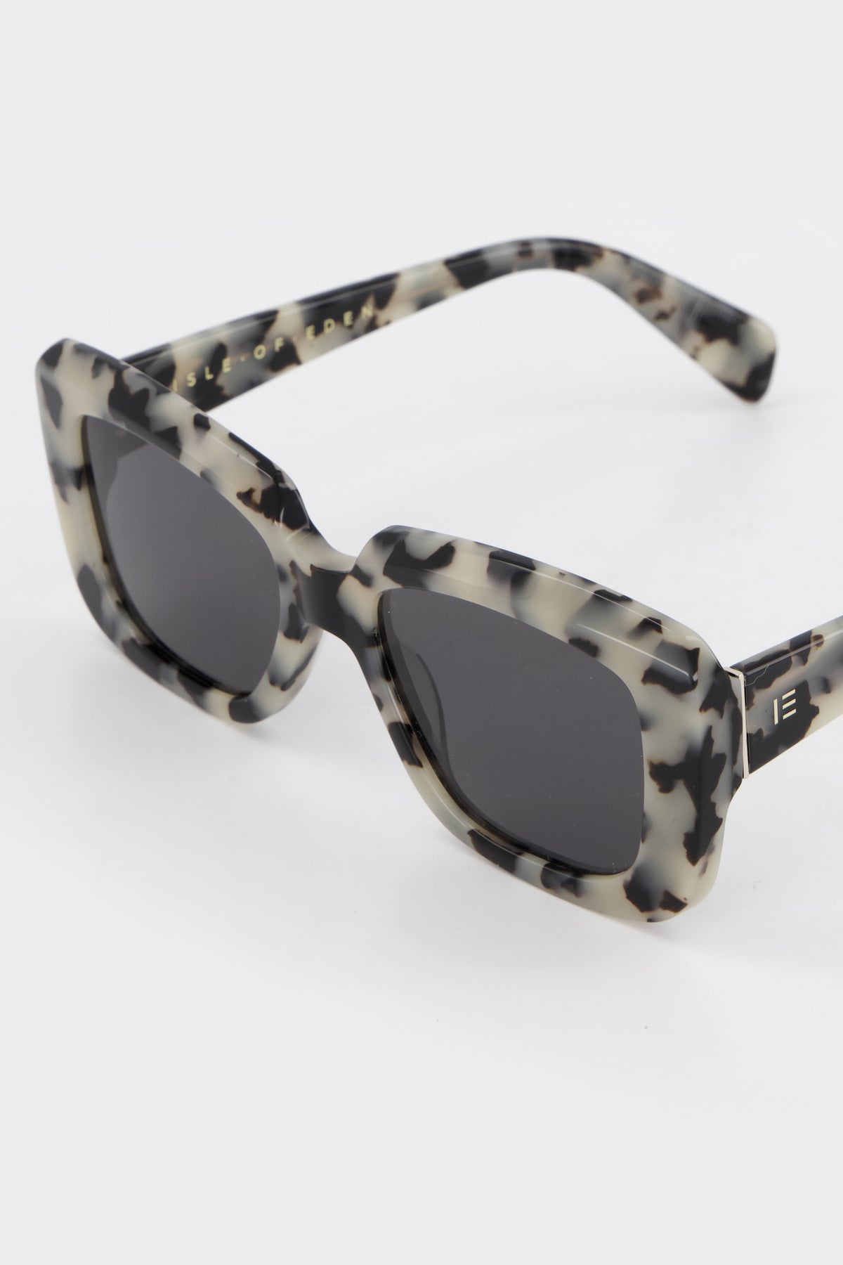 Close-up of Isle of Eden Pia white tortoise sunglasses showing bold rectangular frame and brand lettering