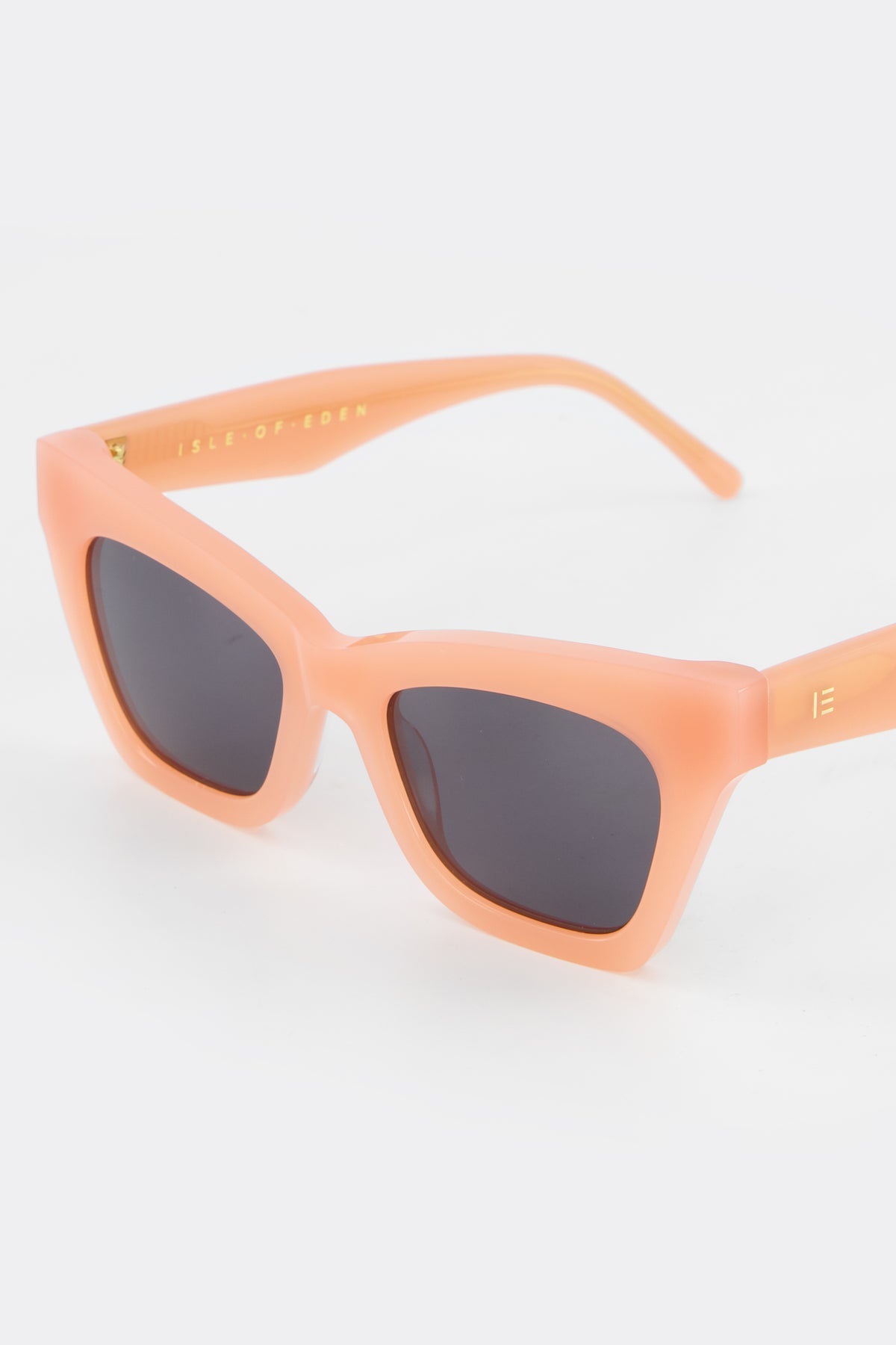 Close-up of Isle of Eden Sienna blush sunglasses showing angular cat-eye frame and brand lettering