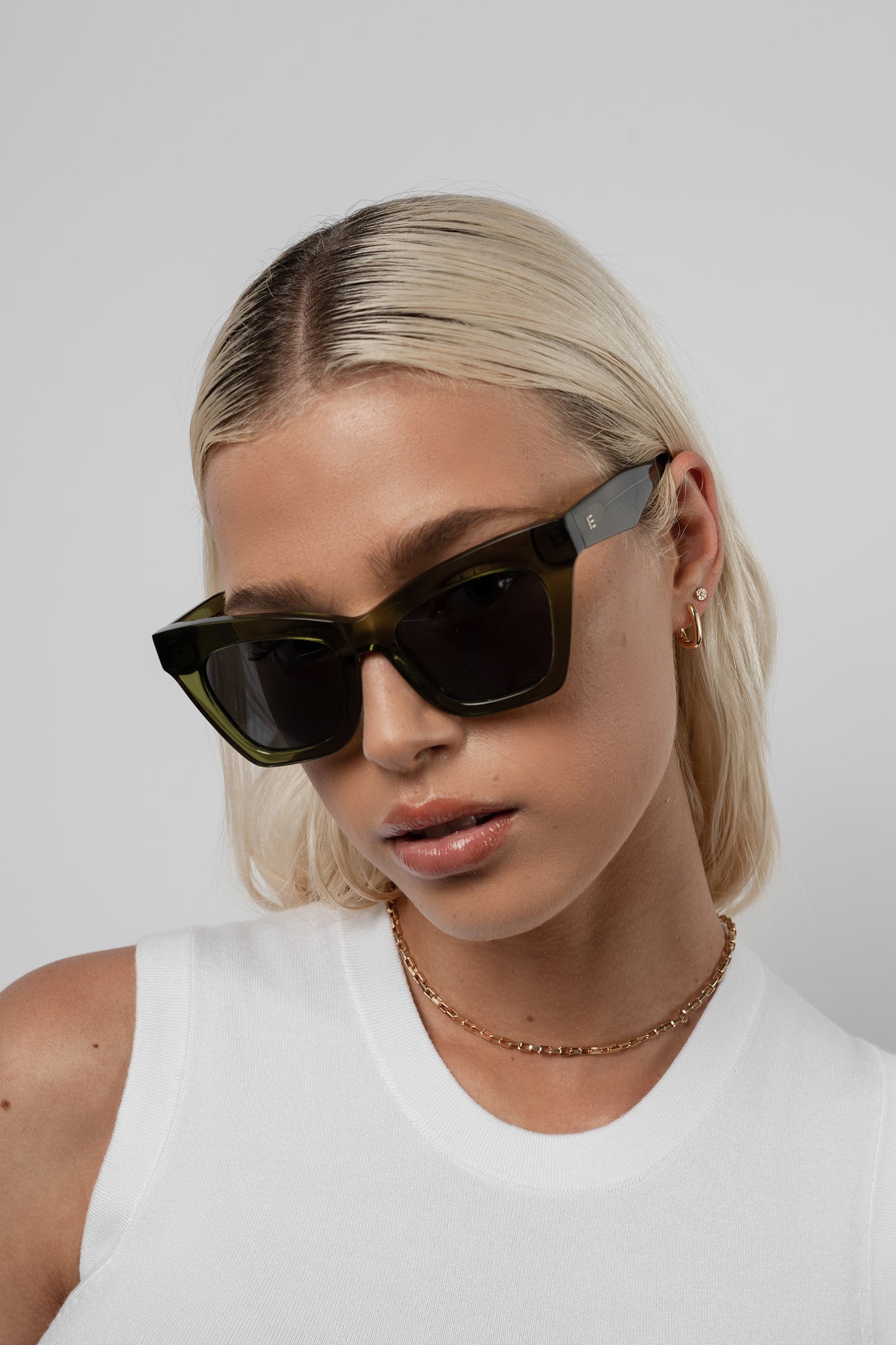 Woman wearing Isle of Eden Sienna bottle green sunglasses, front-facing portrait looking down