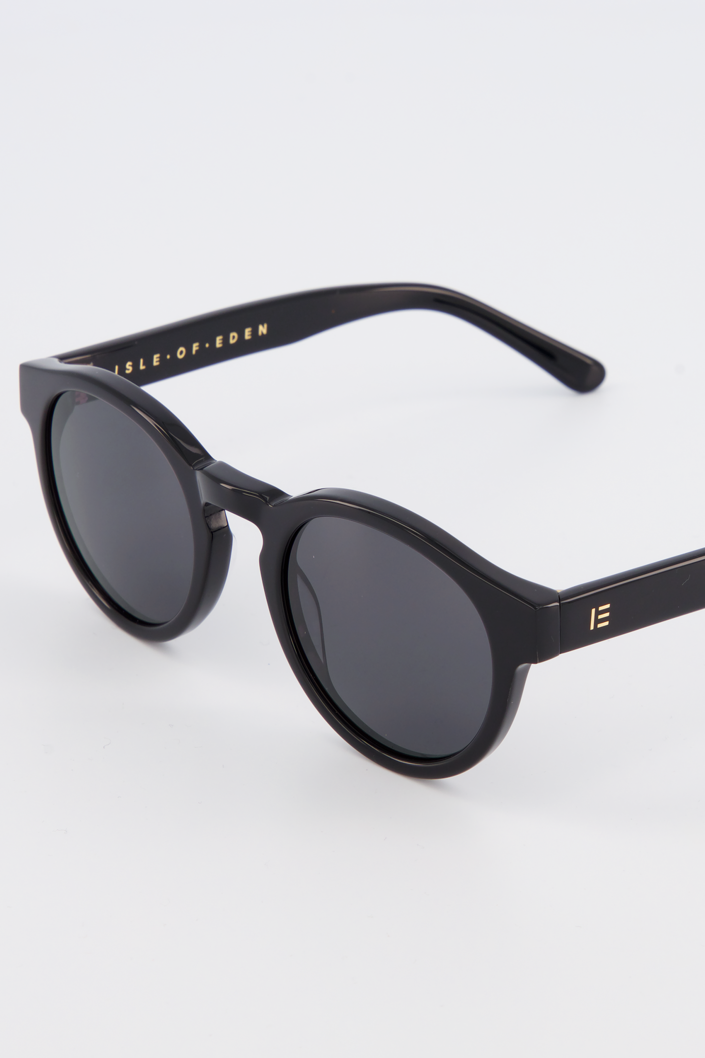 Close-up of Isle of Eden Eddie black sunglasses showing round frame and brand lettering