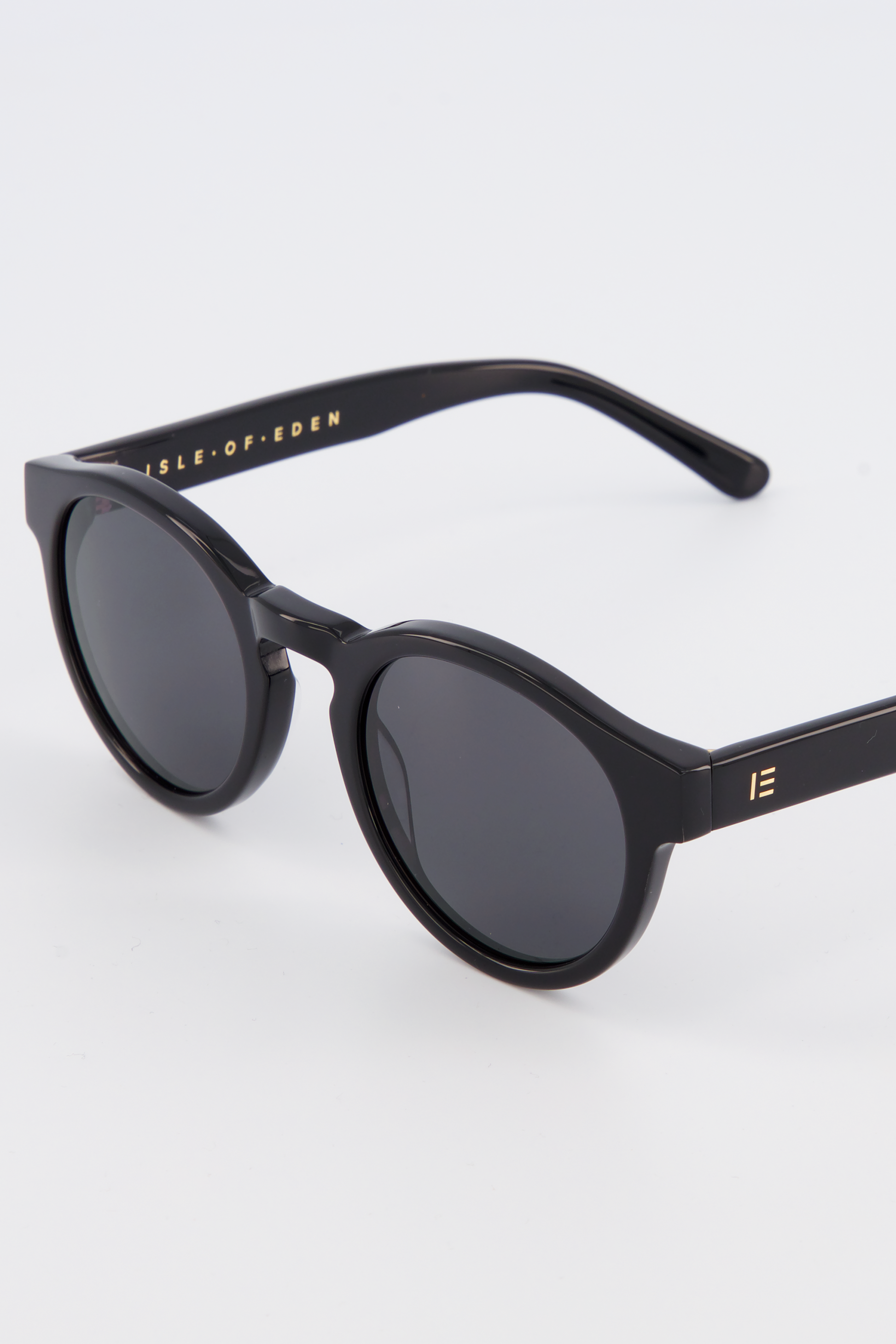 Close-up of Isle of Eden Eddie black sunglasses showing round frame and brand lettering