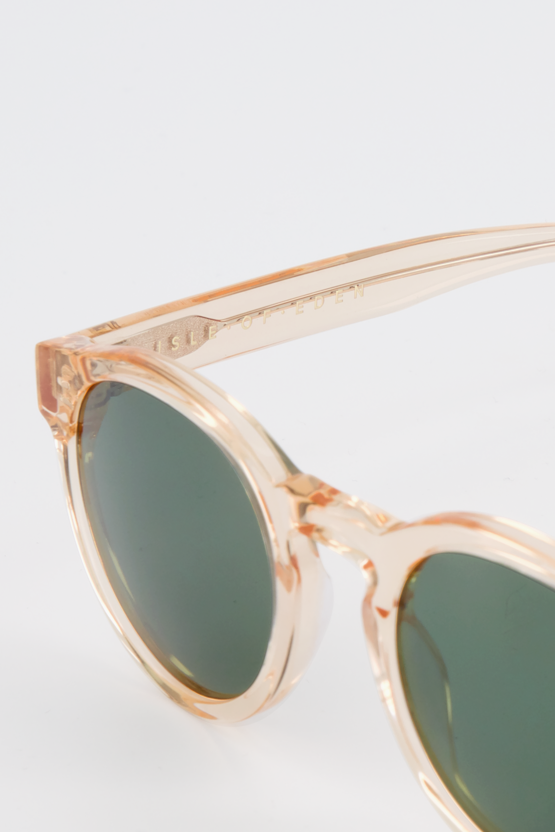 Close-up of Isle of Eden Eddie champagne sunglasses showing round frame and brand lettering