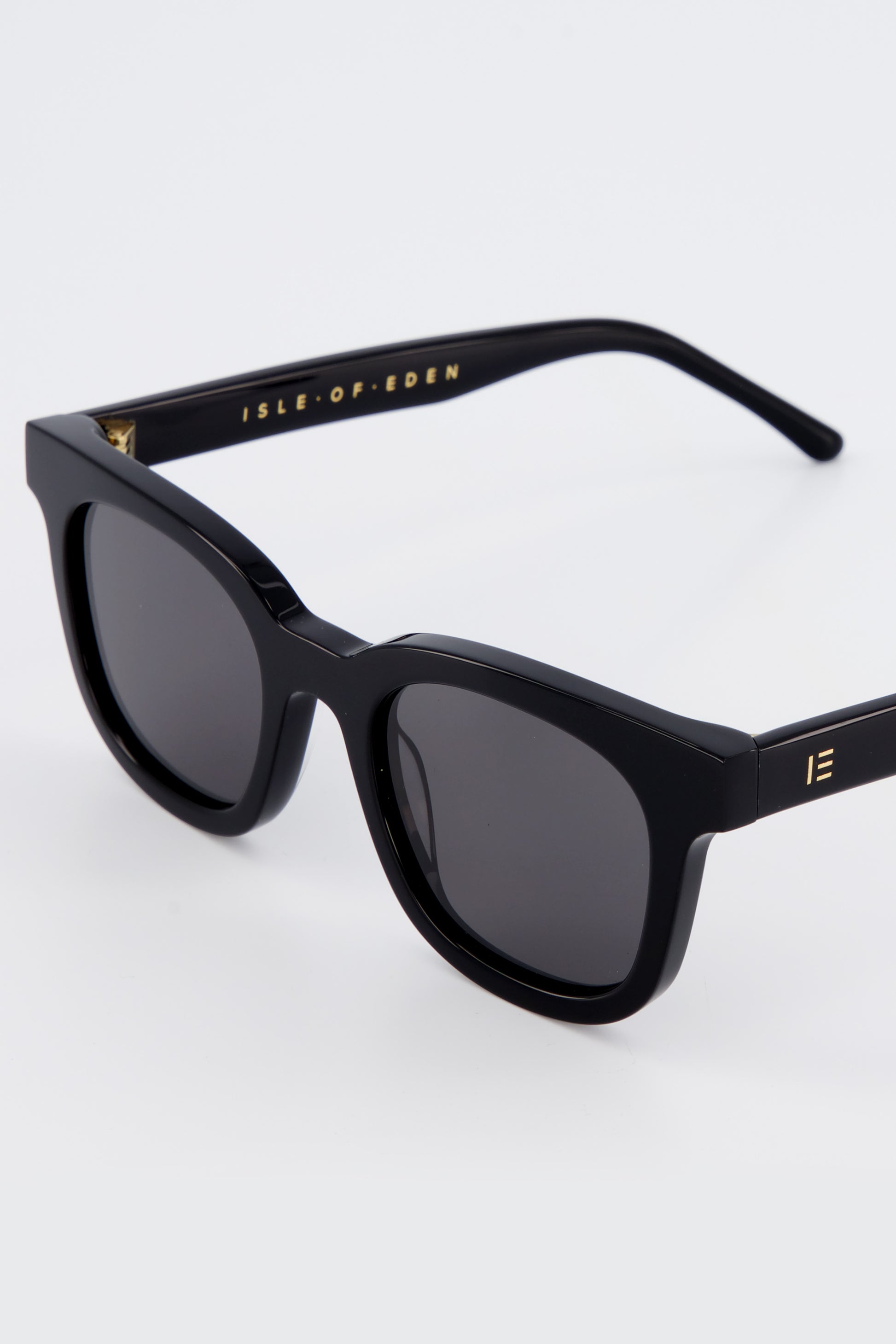 Close-up of Isle of Eden Eugene black sunglasses showing flat brow frame and brand lettering