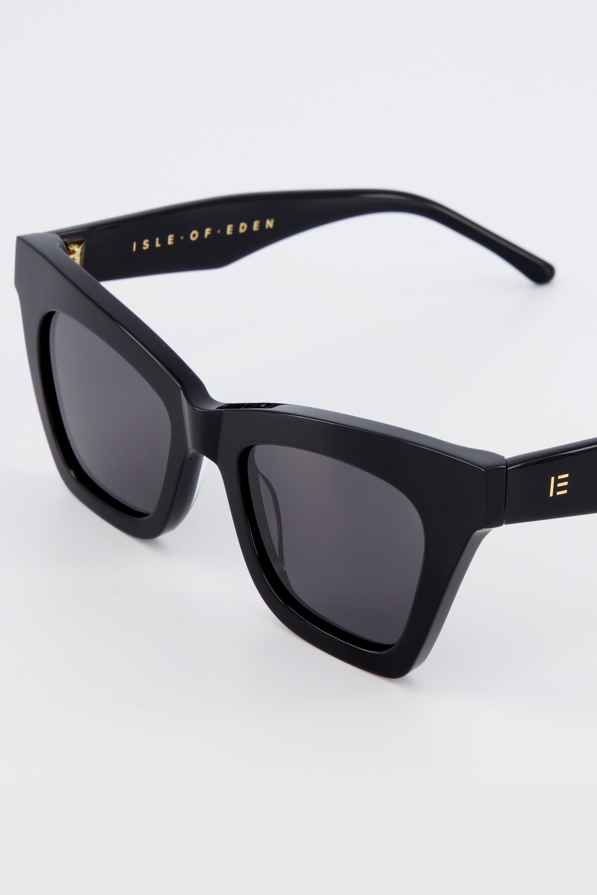 Close-up of Isle of Eden Sienna black sunglasses showing angular cat-eye frame and brand lettering
